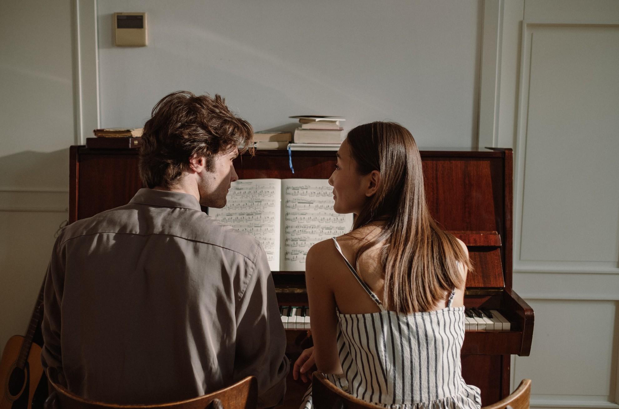 Un homme et une femme discutant devant un piano.