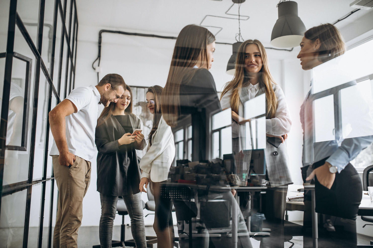 Plusieurs hommes et femmes discutent debout dans un bureau.