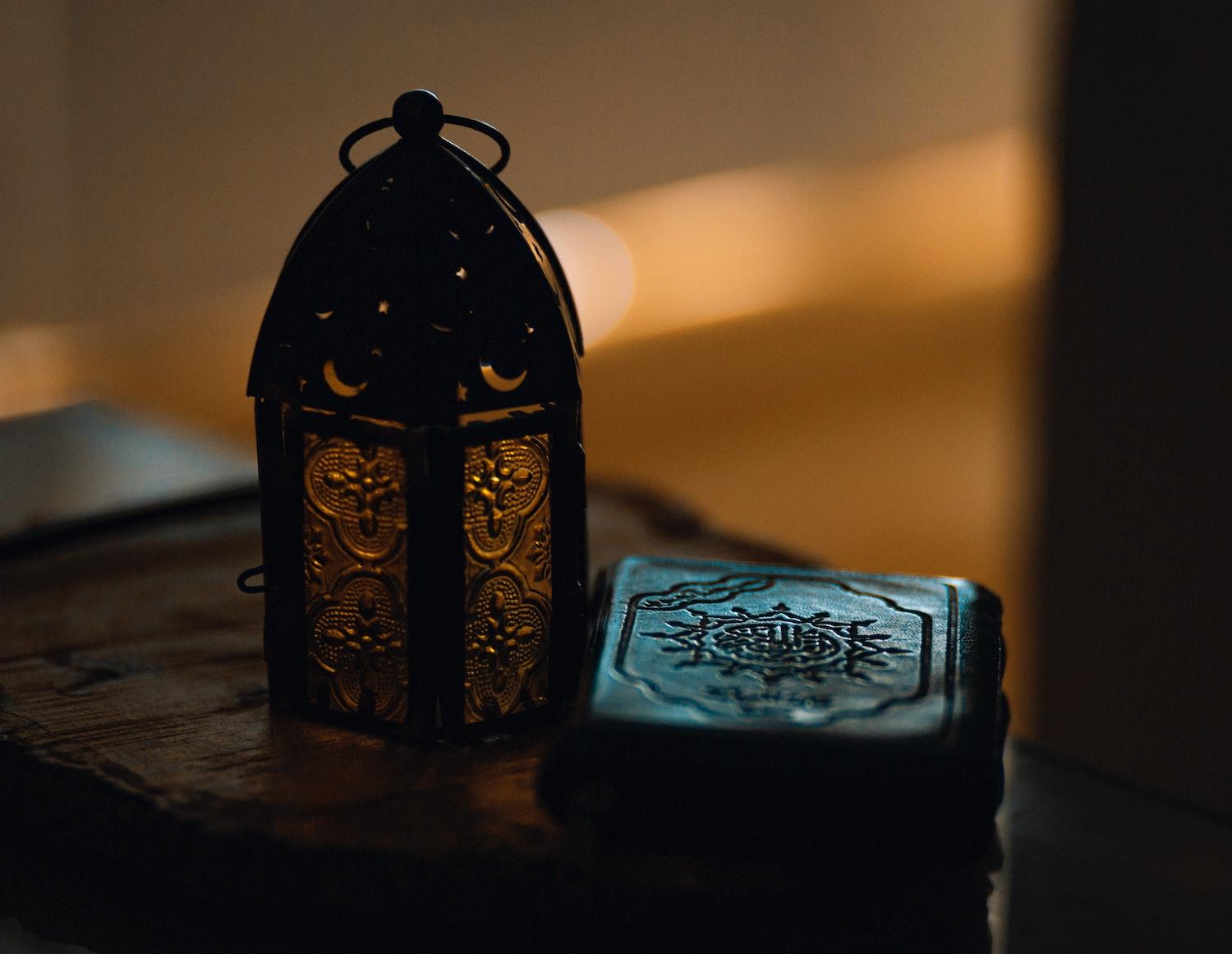 Petite lanterne du Ramadan avec le coran posé à côté.