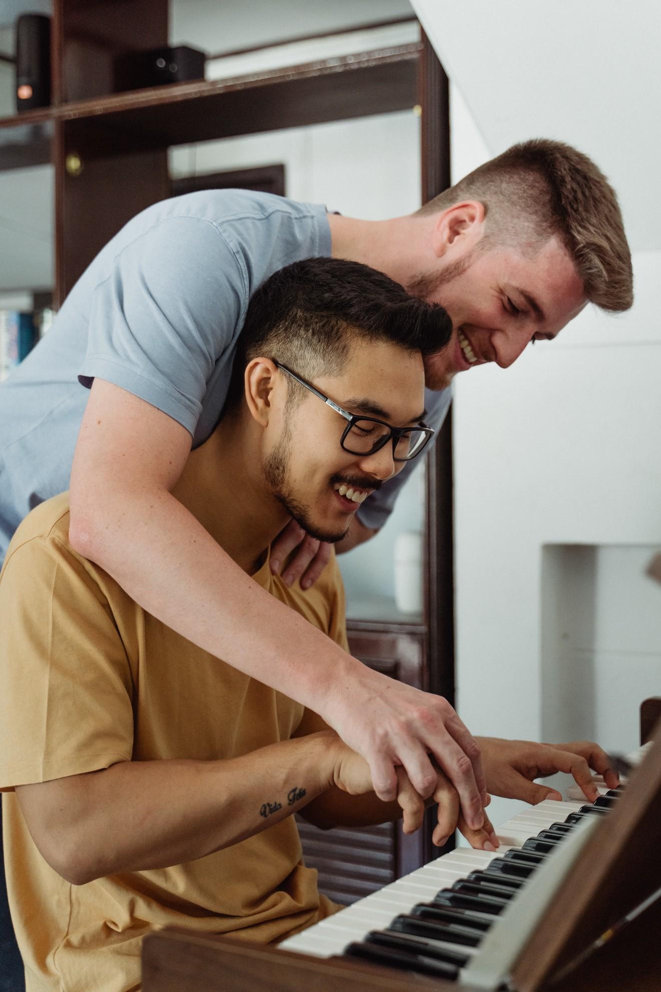 Deux hommes s'amusant ensemble en jouant du piano.