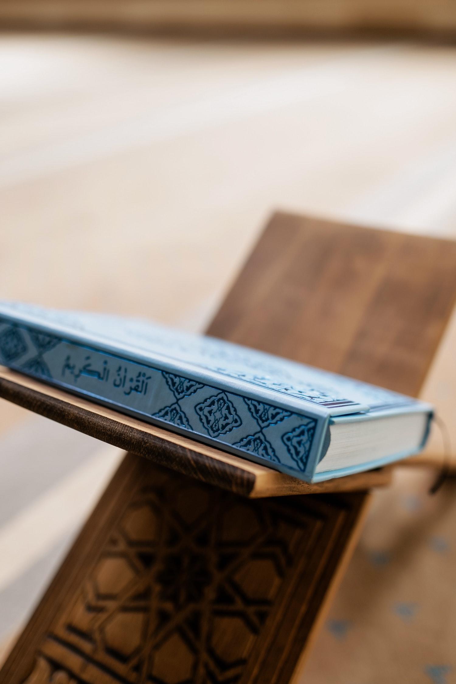 Un Coran est posé sur un petit tabouret en bois.