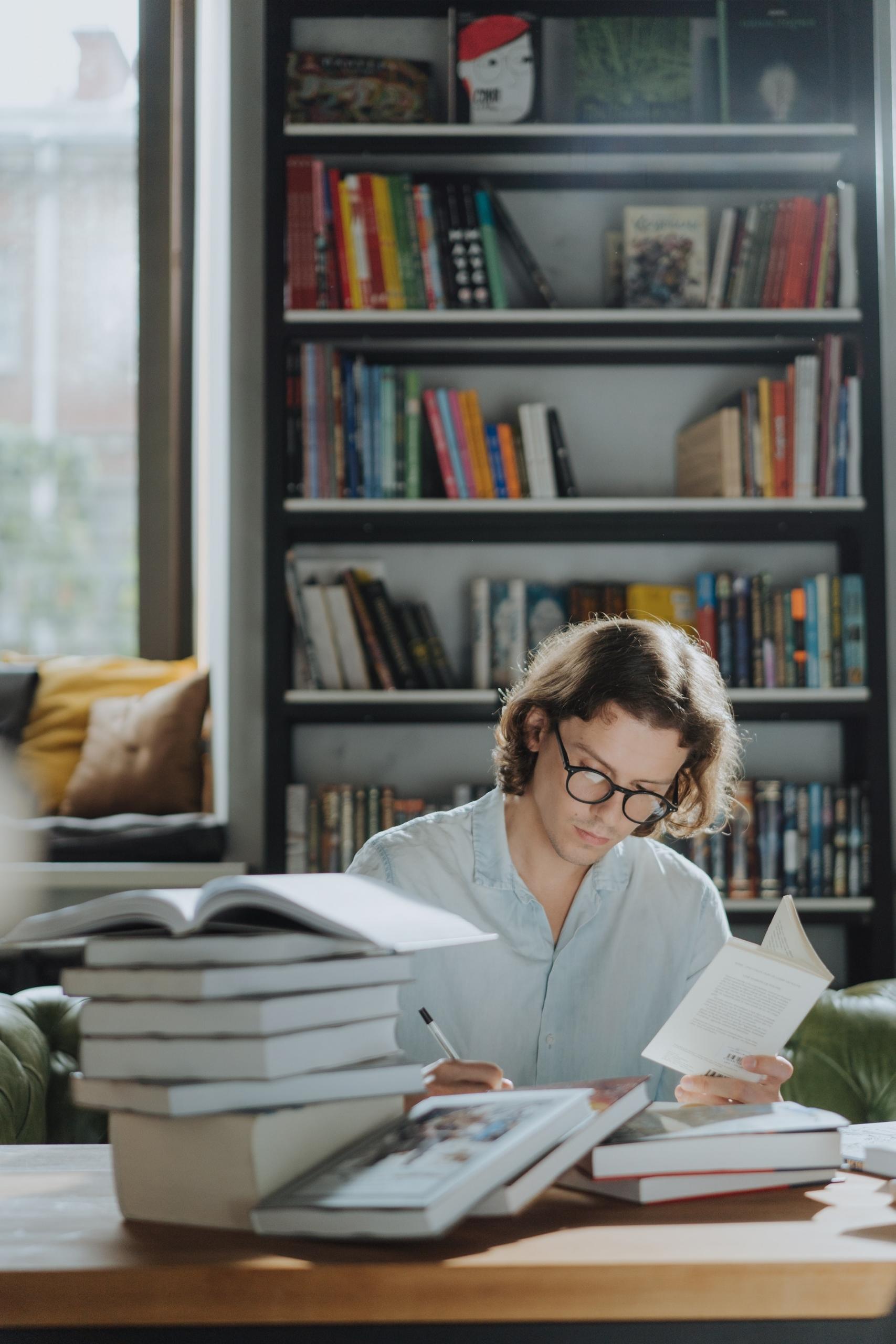 jeune personne en train d'étudier entourée de livres
