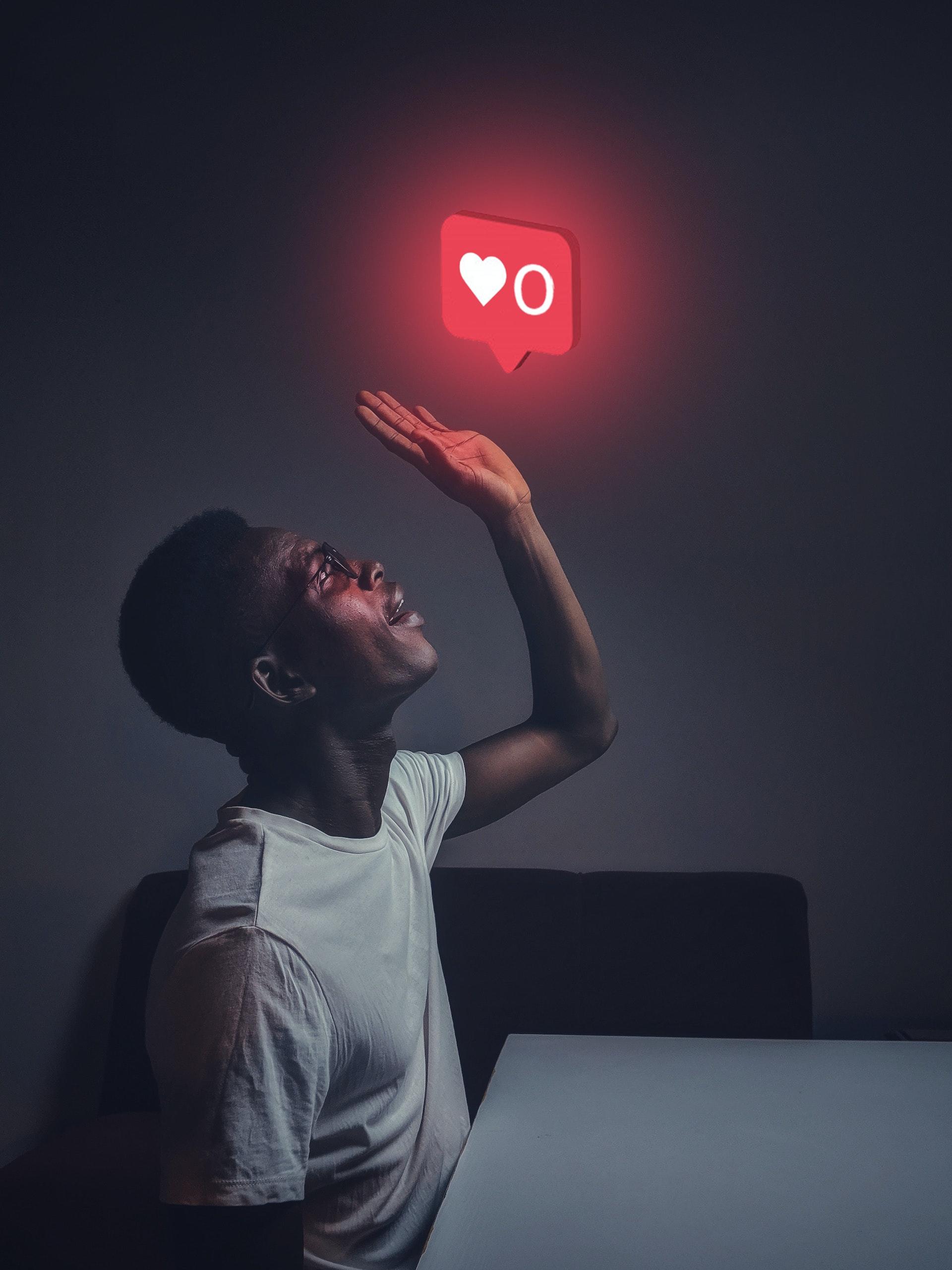 personne en train de regarder un néon avec un coeur de type like d'Instagram