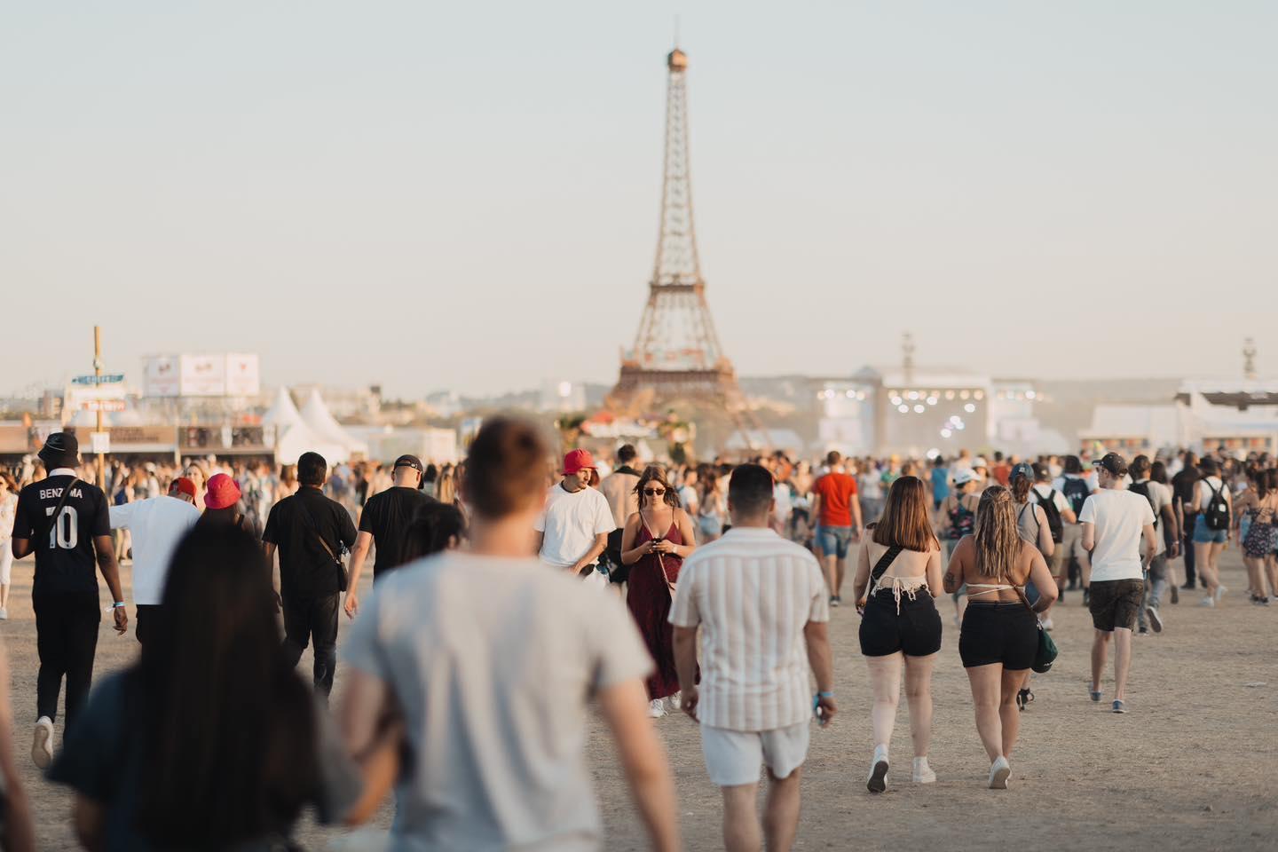 Festivaliers marchant sur le site du festival Lollapalooza avec la Tour Eiffel en fond.