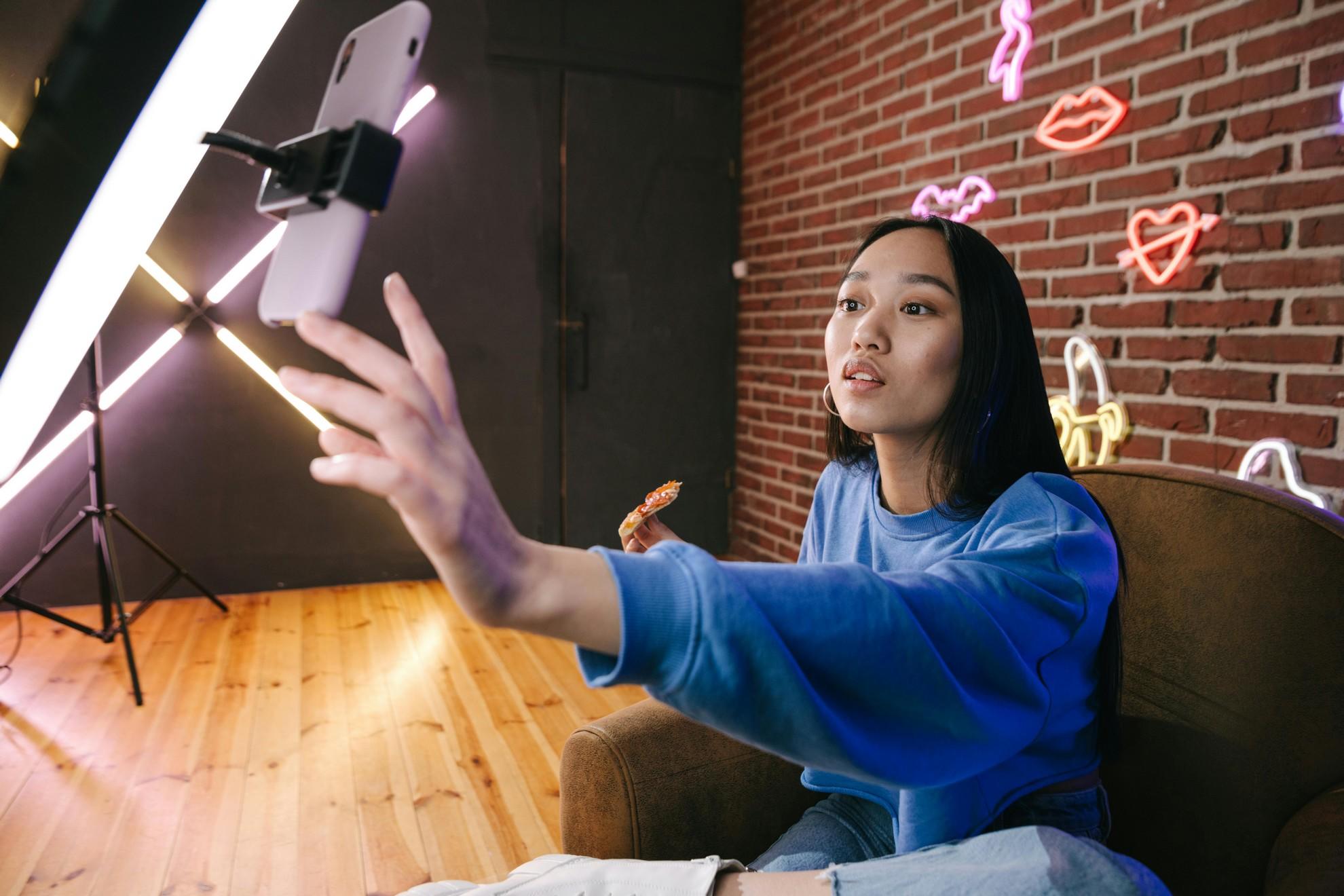 Une jeune femme en train de se filmer avec son smartphone.