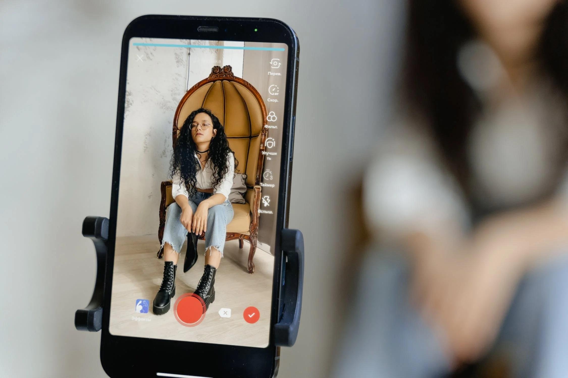 Une influenceuse se filme avec un smartphone.