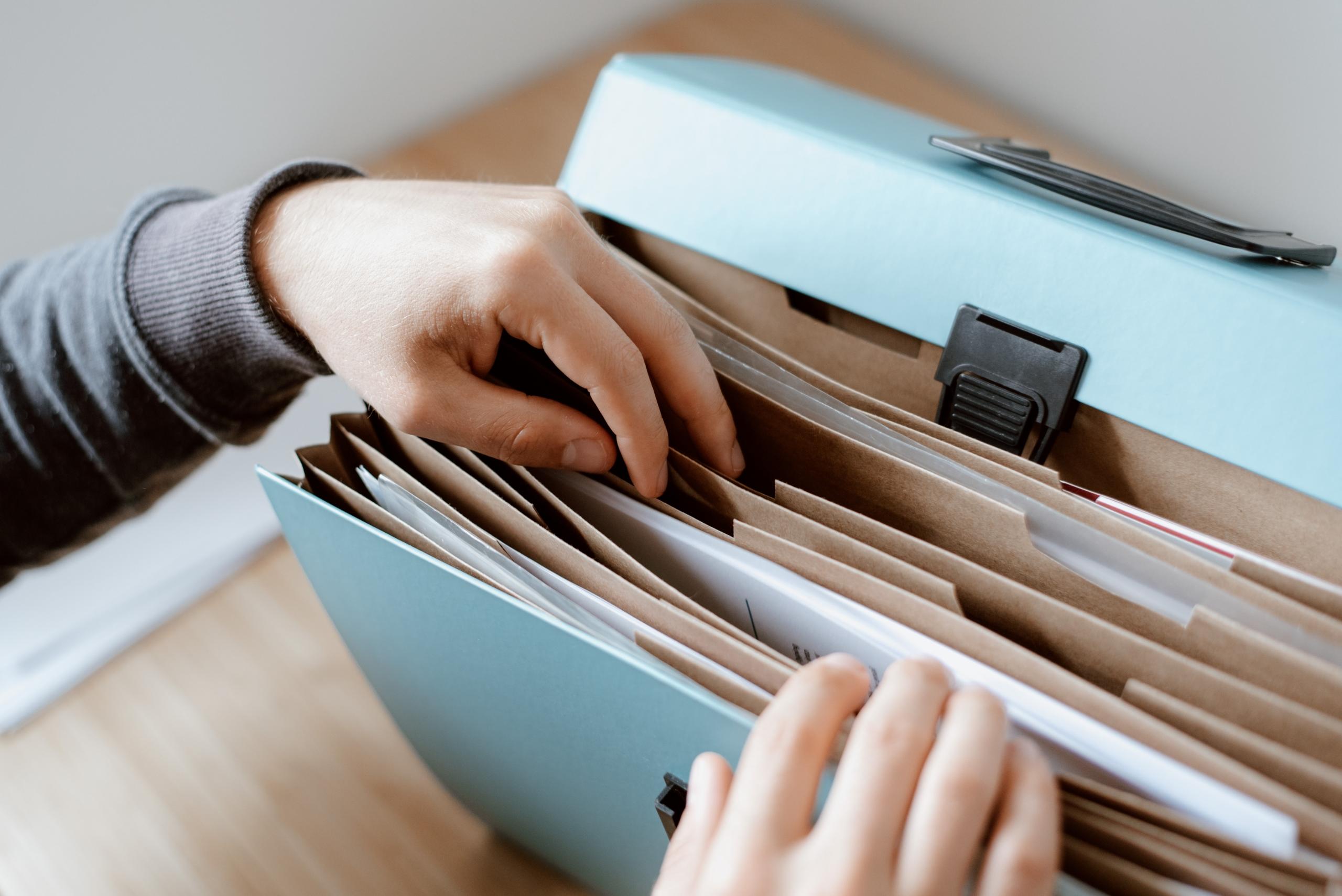 une personne cherchant un papier dans une sacoche de documents