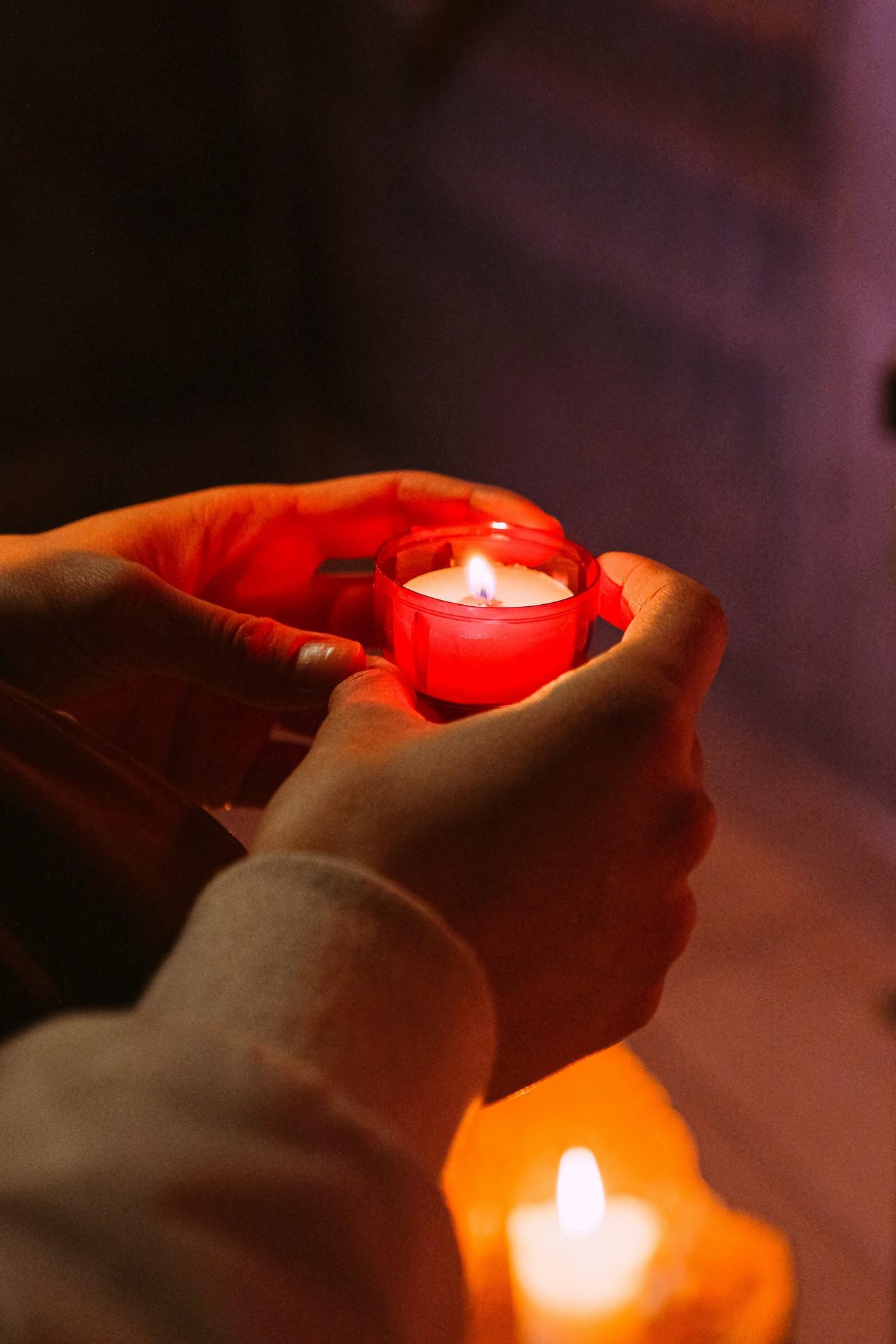 Une personne tenant un lumignon rouge.
