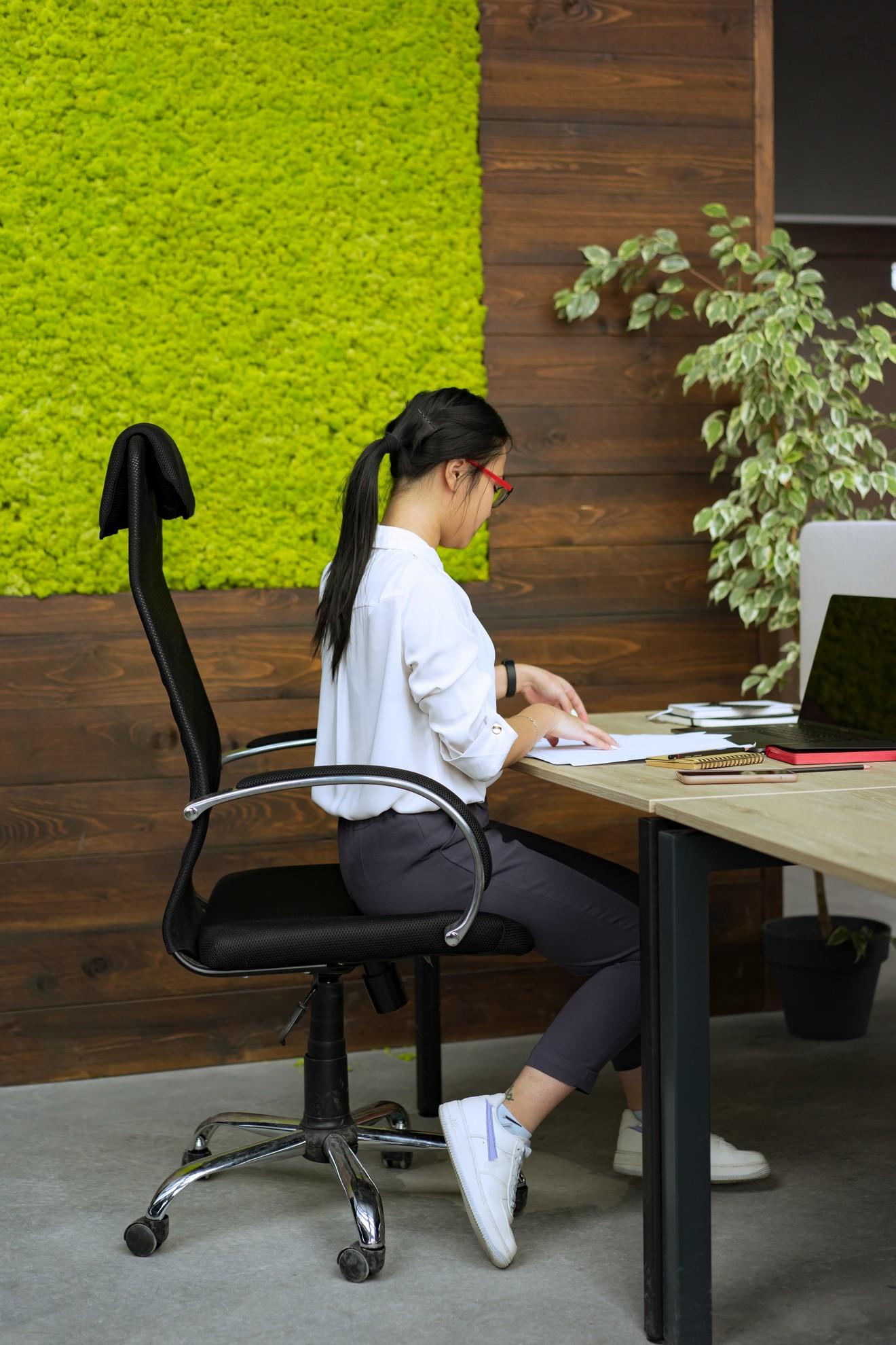 Une femme assise en bout de chaise derrière son bureau.
