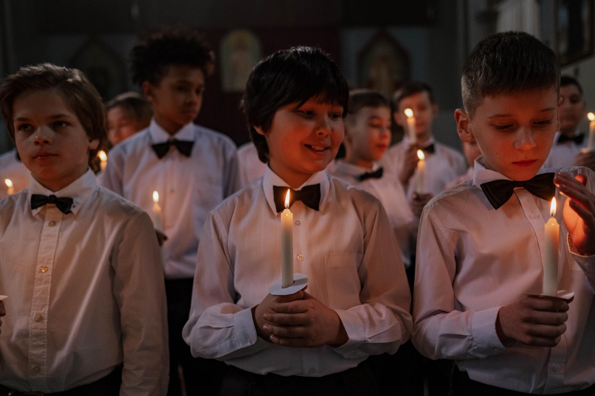 Des garçons tenant des cierges lors de la messe.
