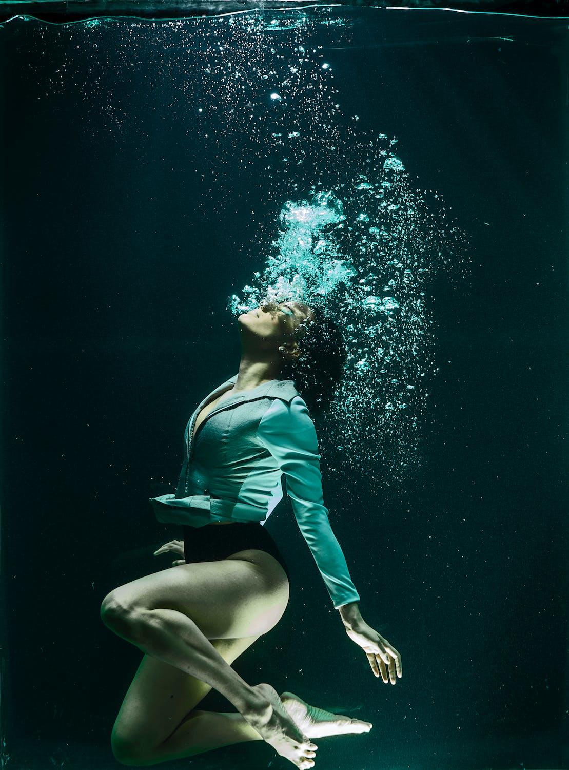 Une femme fait des bulles sous l'eau.
