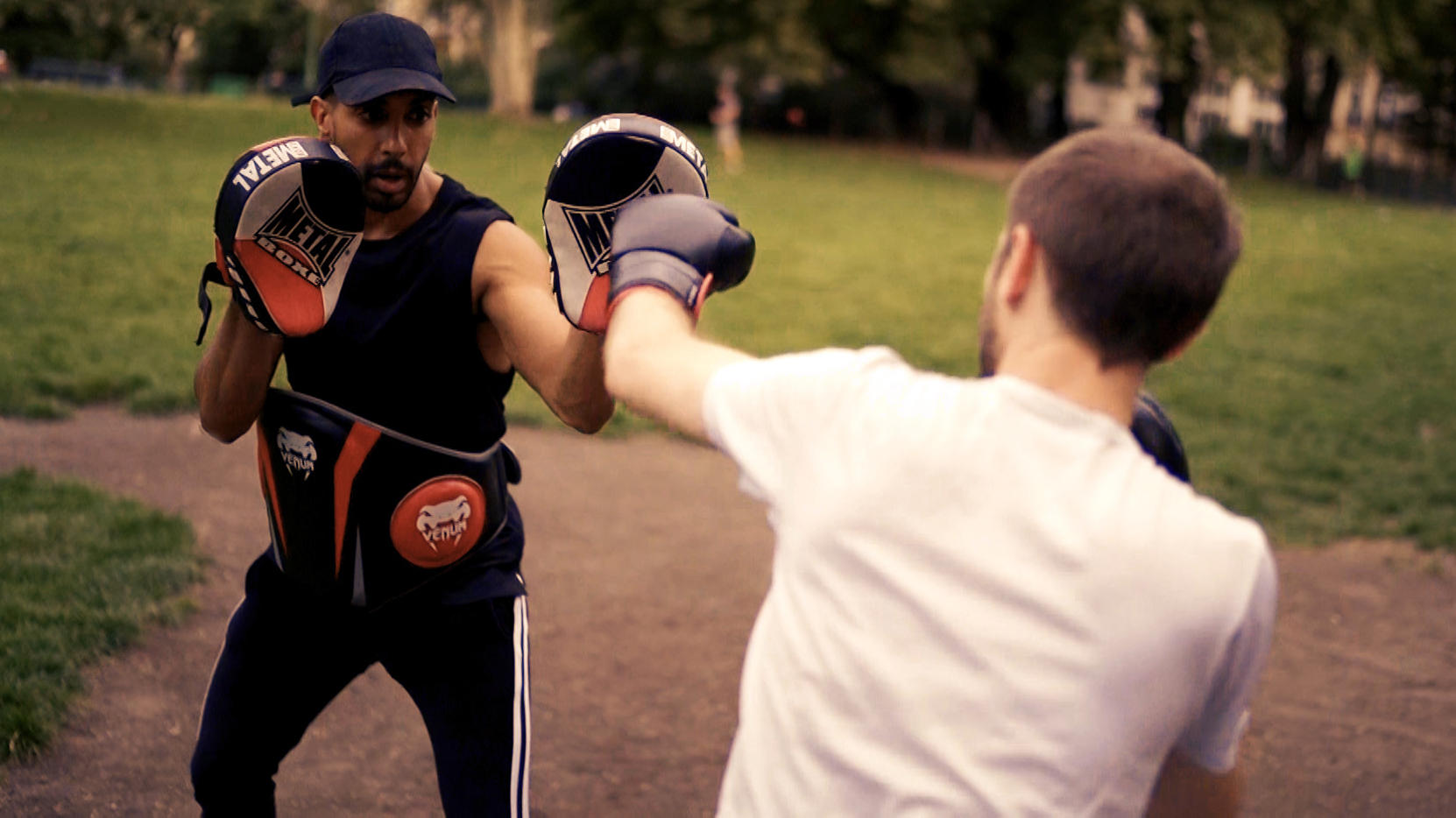 Homme prenant un cours de boxe avec un professeur en extérieur.