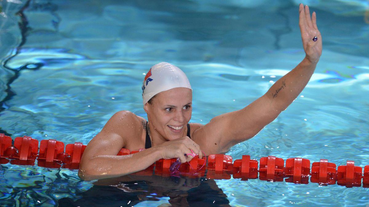 Laure Manadou salue de la main dans une piscine.