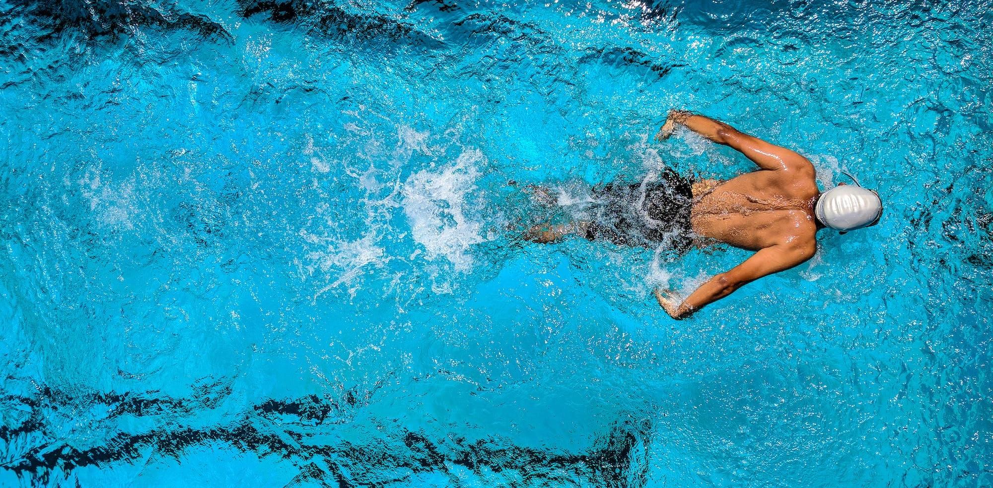 Un homme fait des longueurs dans une piscine.
