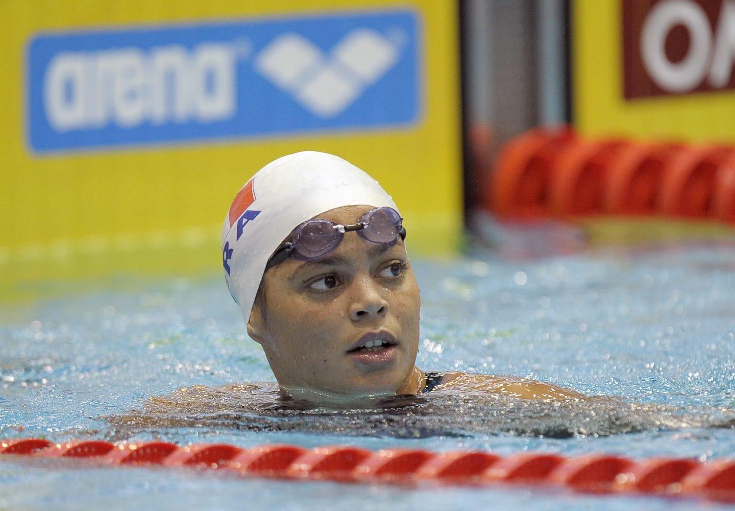 Coralie Balmy est dans une piscine avec un bonnet de bain et des lunettes.