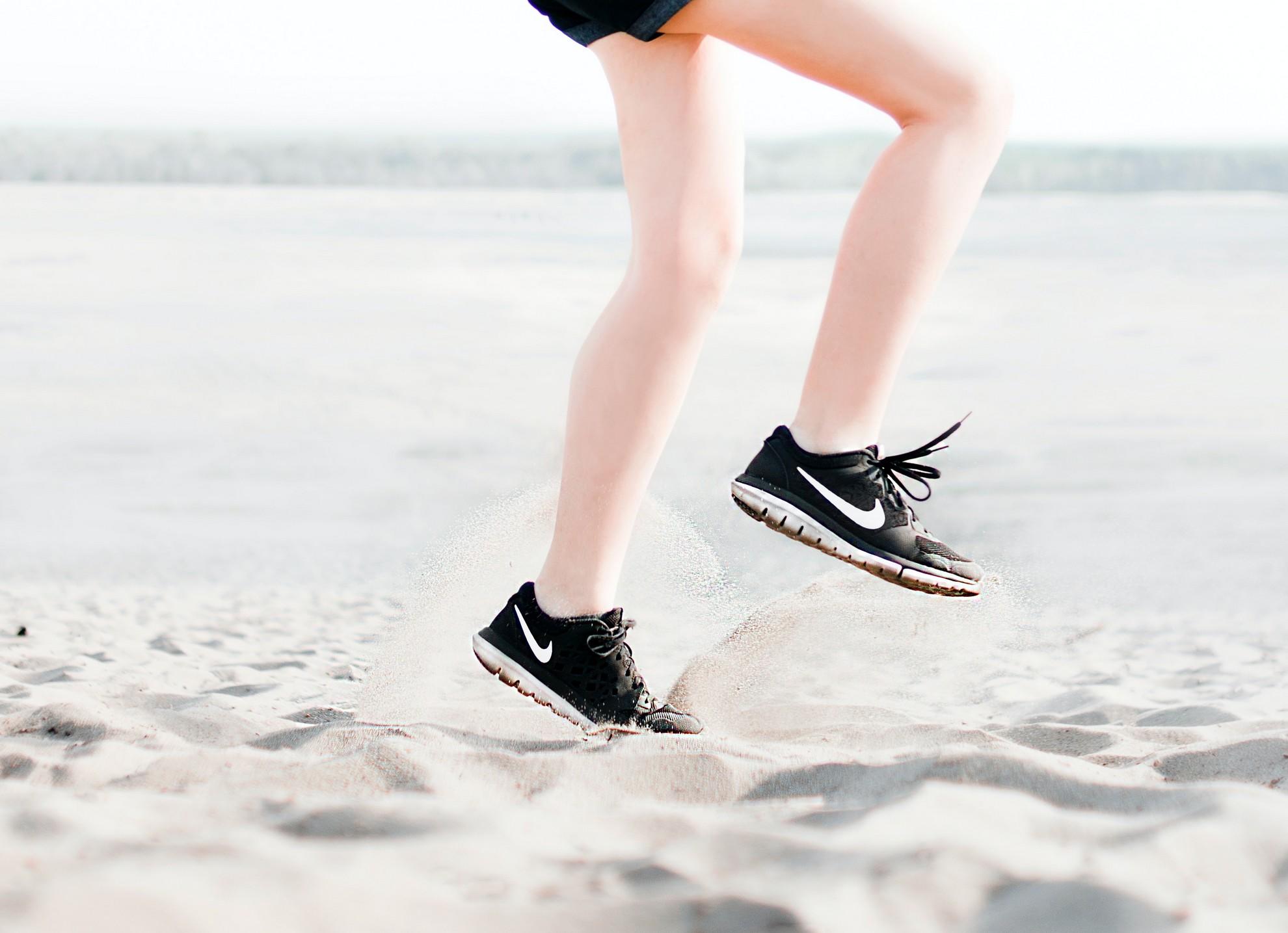 Une personne en train de courir sur le sable fin.