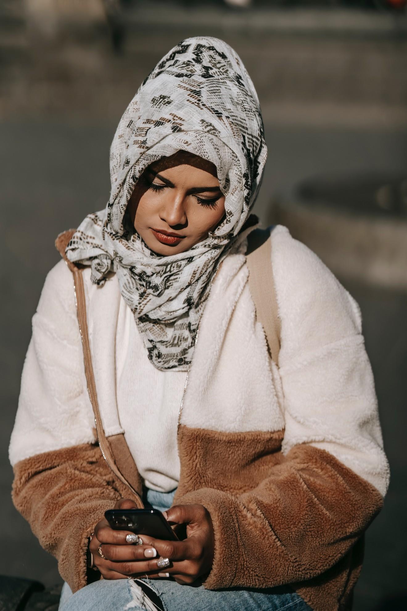 Une jeune femme en train de consulter son smartphone dans la rue.