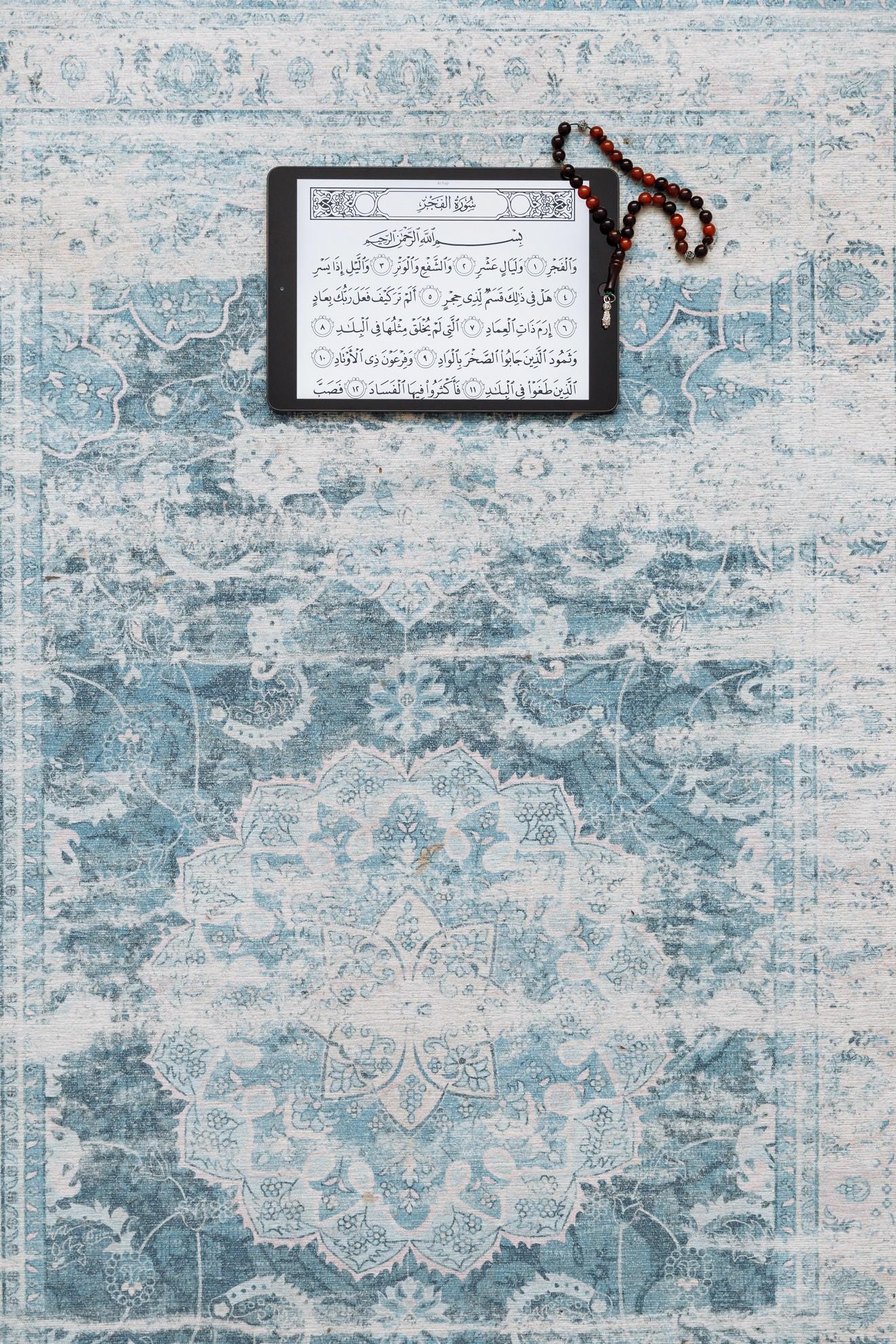 Une tablette tactile avec un texte en arabe sur un tapis bleu.