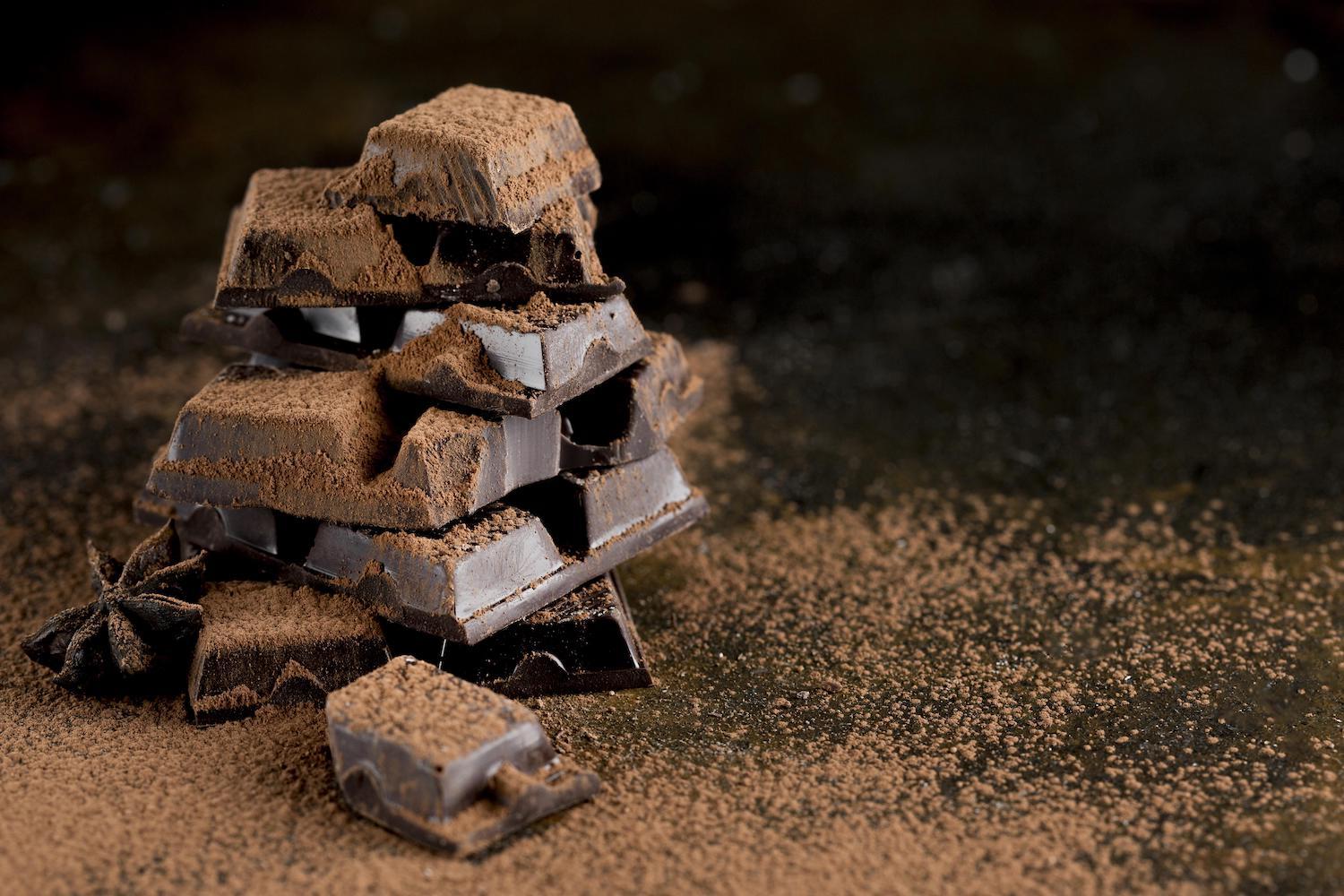 Quelques carrés de chocolat sont superposés avec du chocolat en poudre dessus