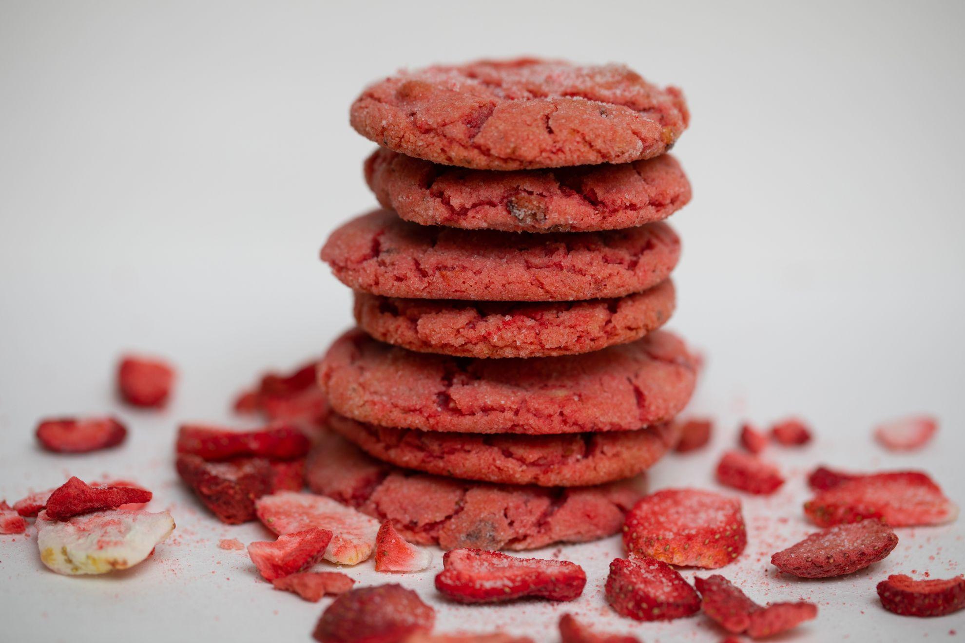 Un tas de cookies à la fraise parsemé de morceaux de fraises fraîches.