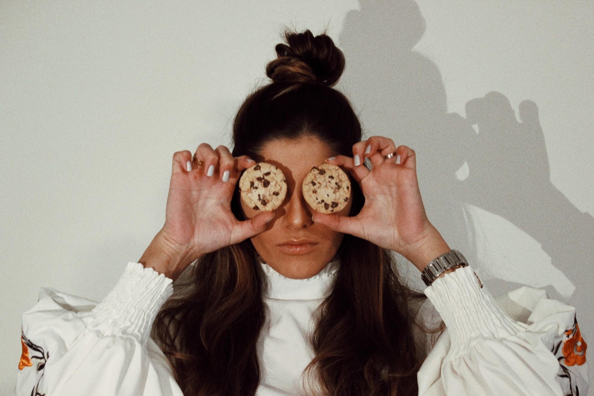 Une femme qui place des cookies devant son visage.
