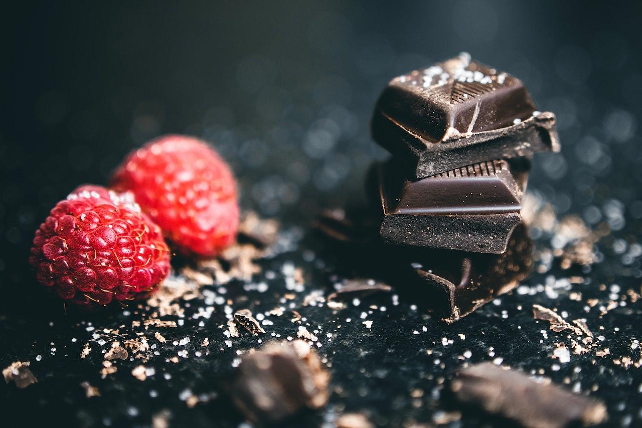 Morceaux de chocolat noir et framboises sur une table noire