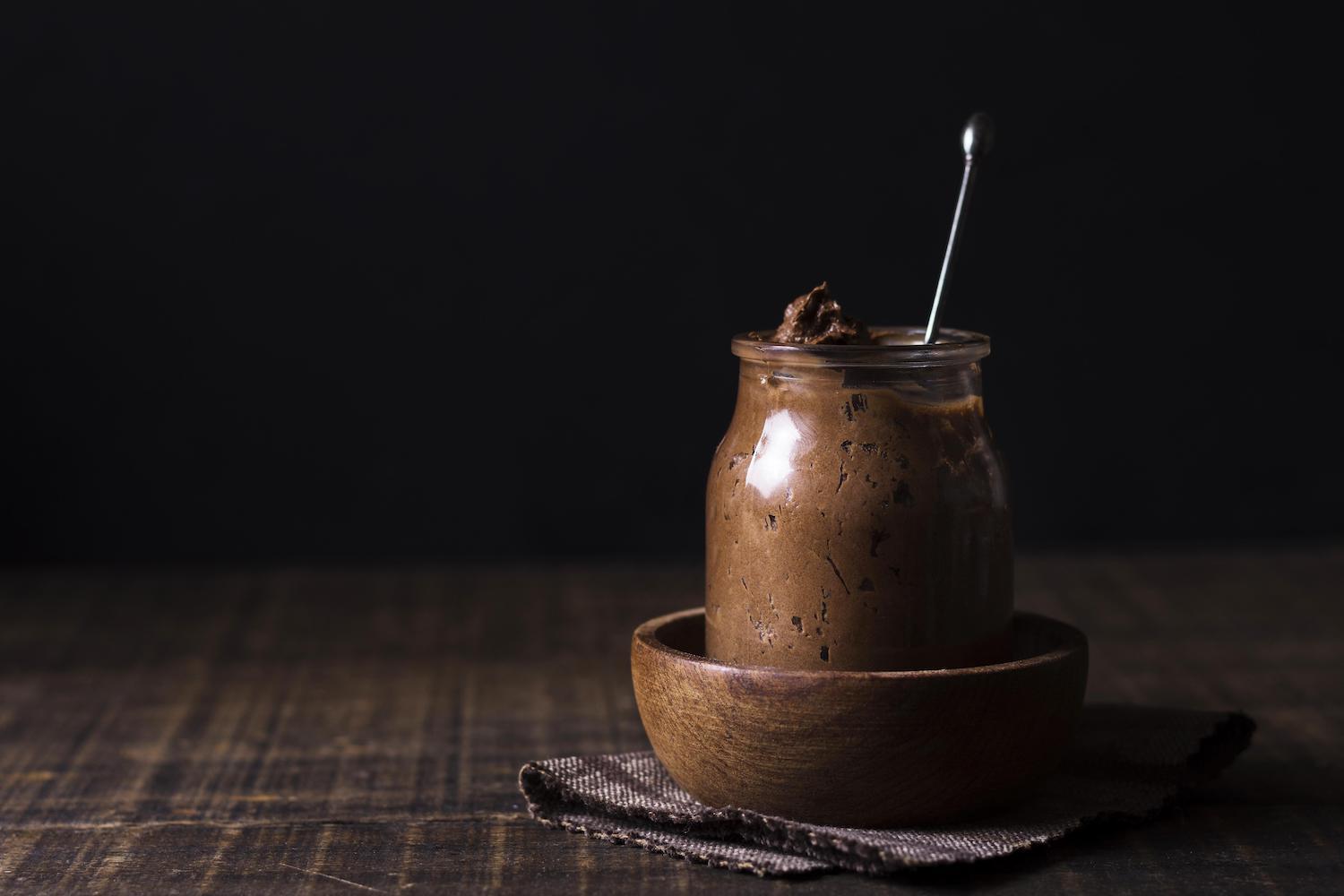 Pot de mousse au chocolat posé sur un torchon sur fond noir