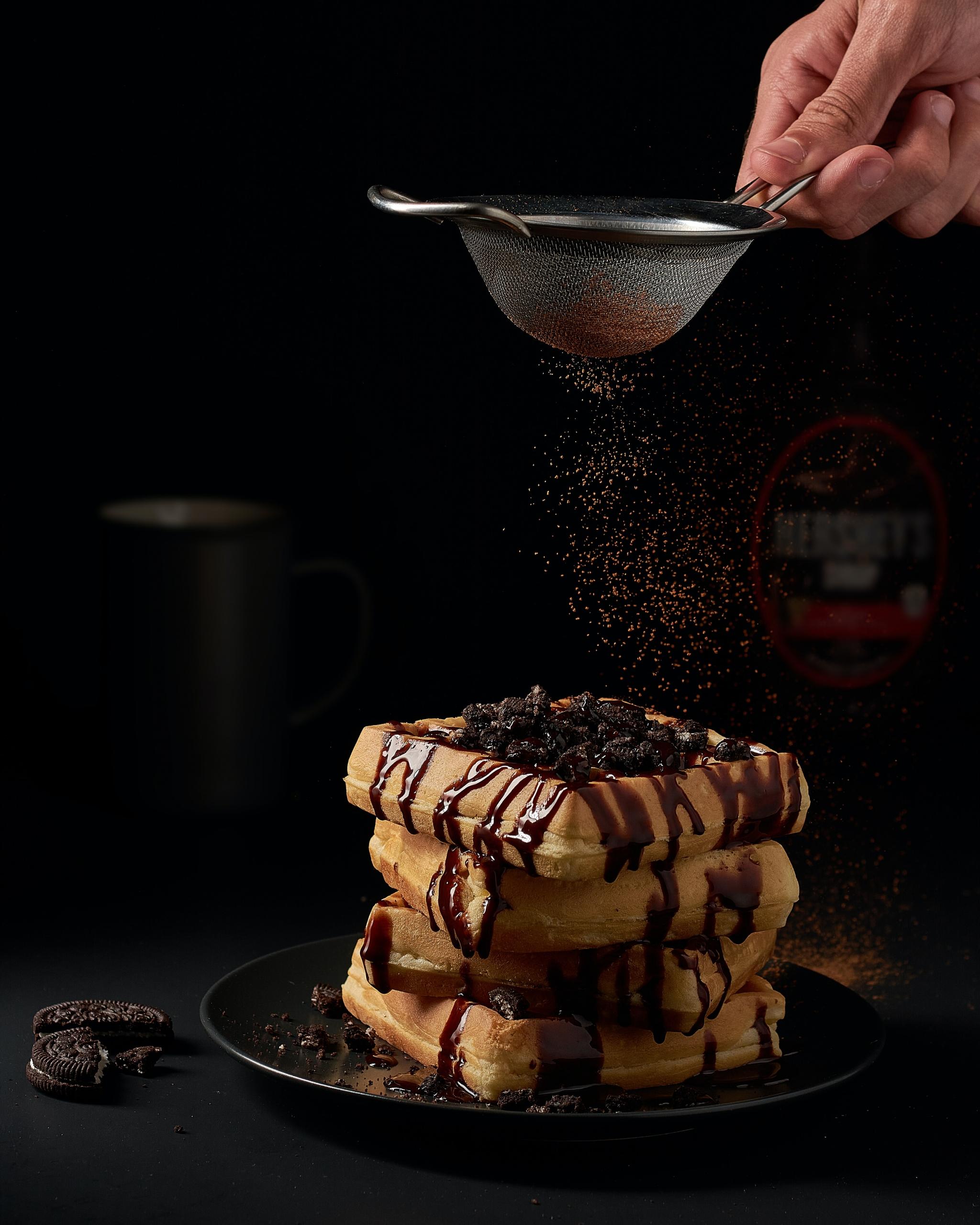 Une poudre de chocolat est déposée sur une pile de gaufres.