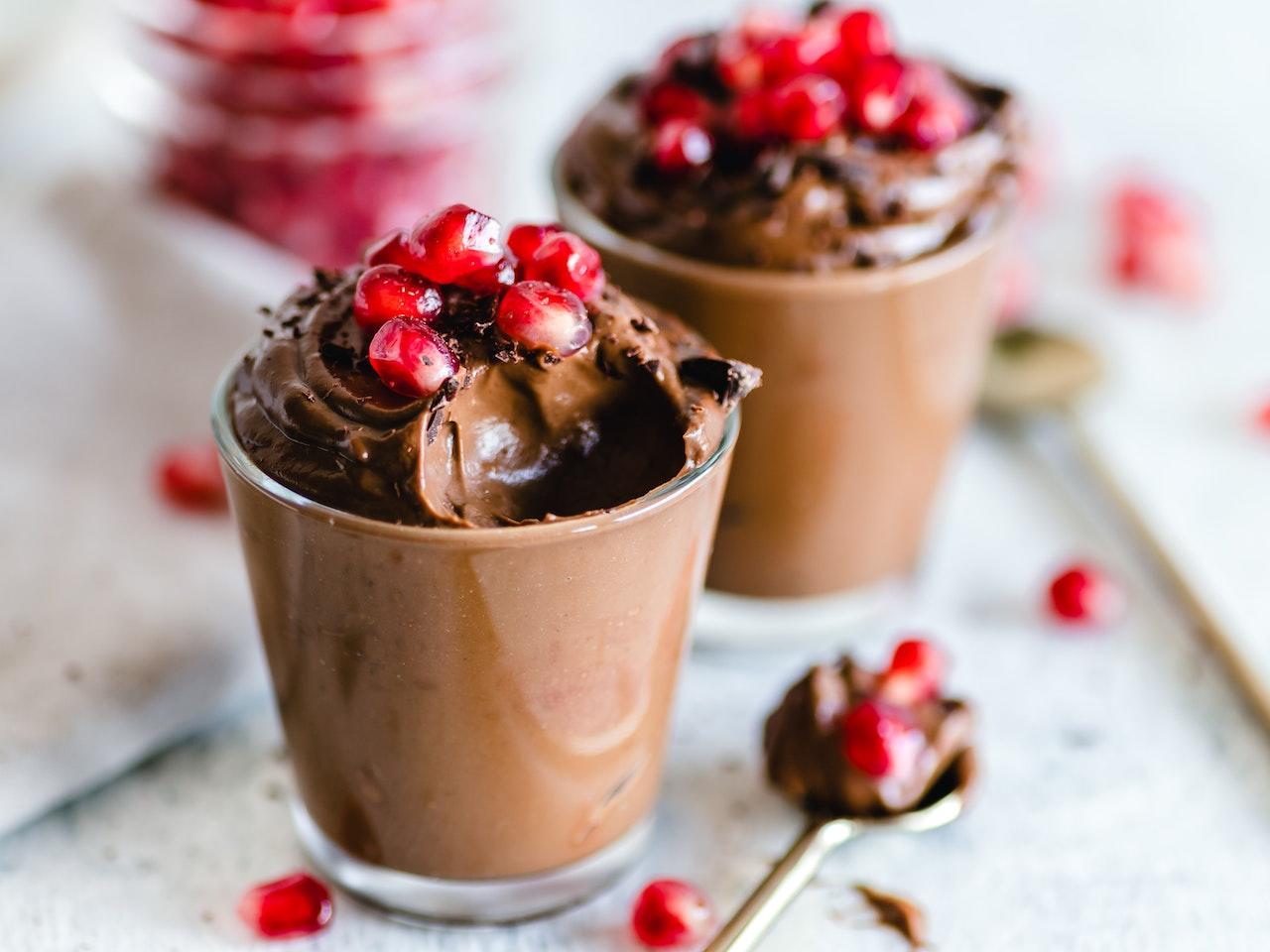 Mousse au chocolat dans un verre avec des morceaux de grenade dessus.