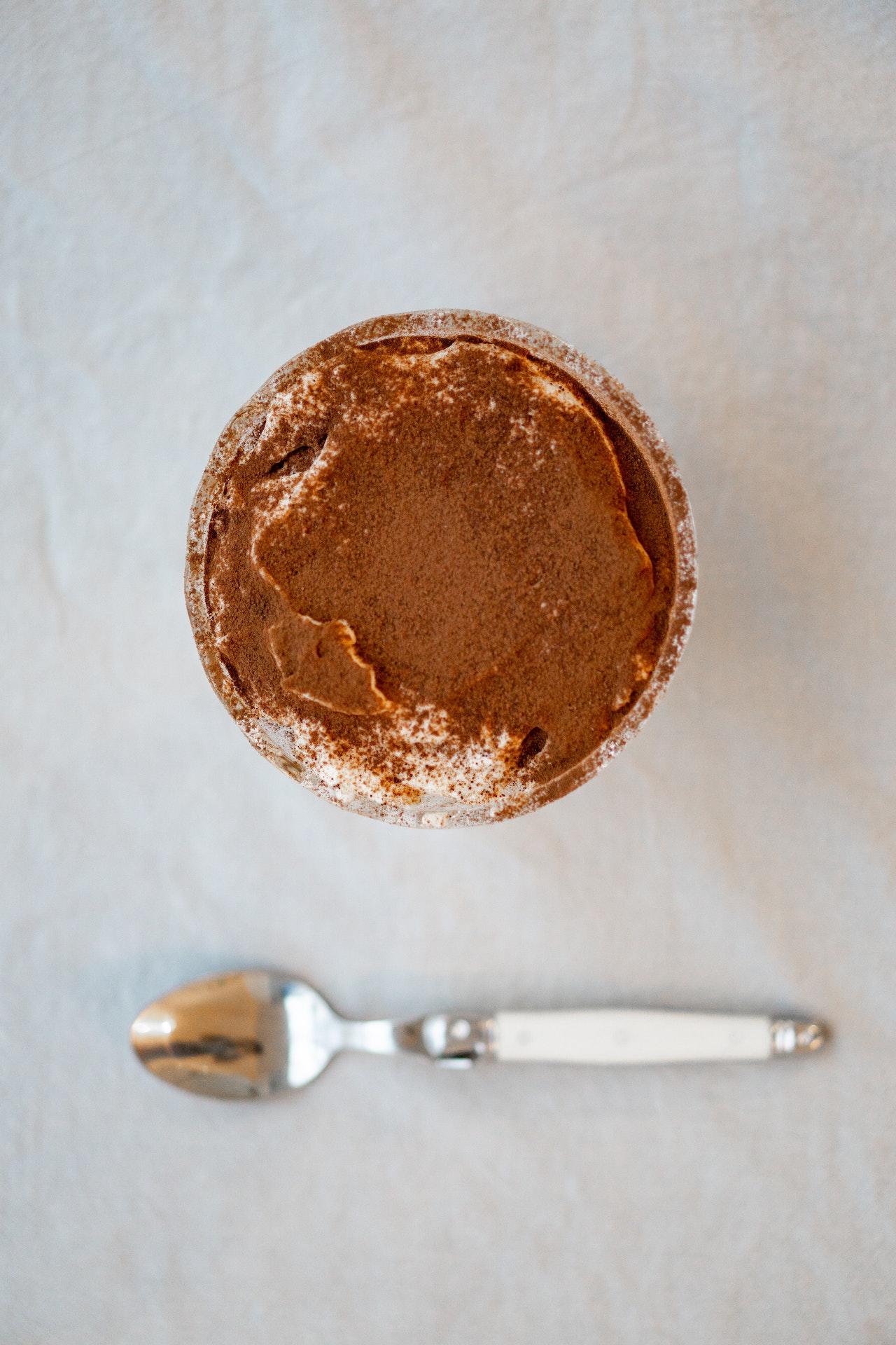 Tiramisu dans un verre vu d'en haut avec une petite cuillère disposée devant.