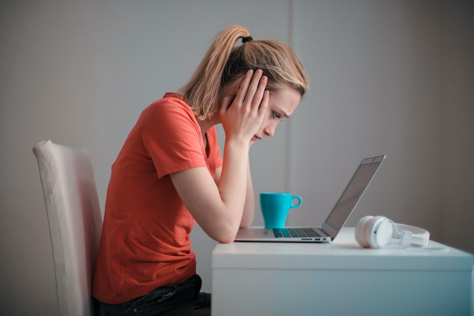 Une femme stressée devant son ordinateur portable.