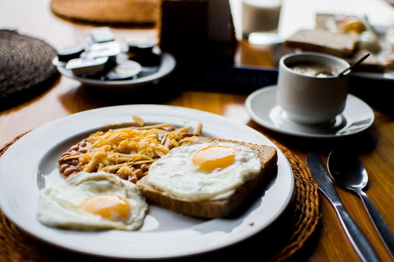 Photo d'un brunch composé d'oeufs, de galette de pommes de terre et d'un café. 