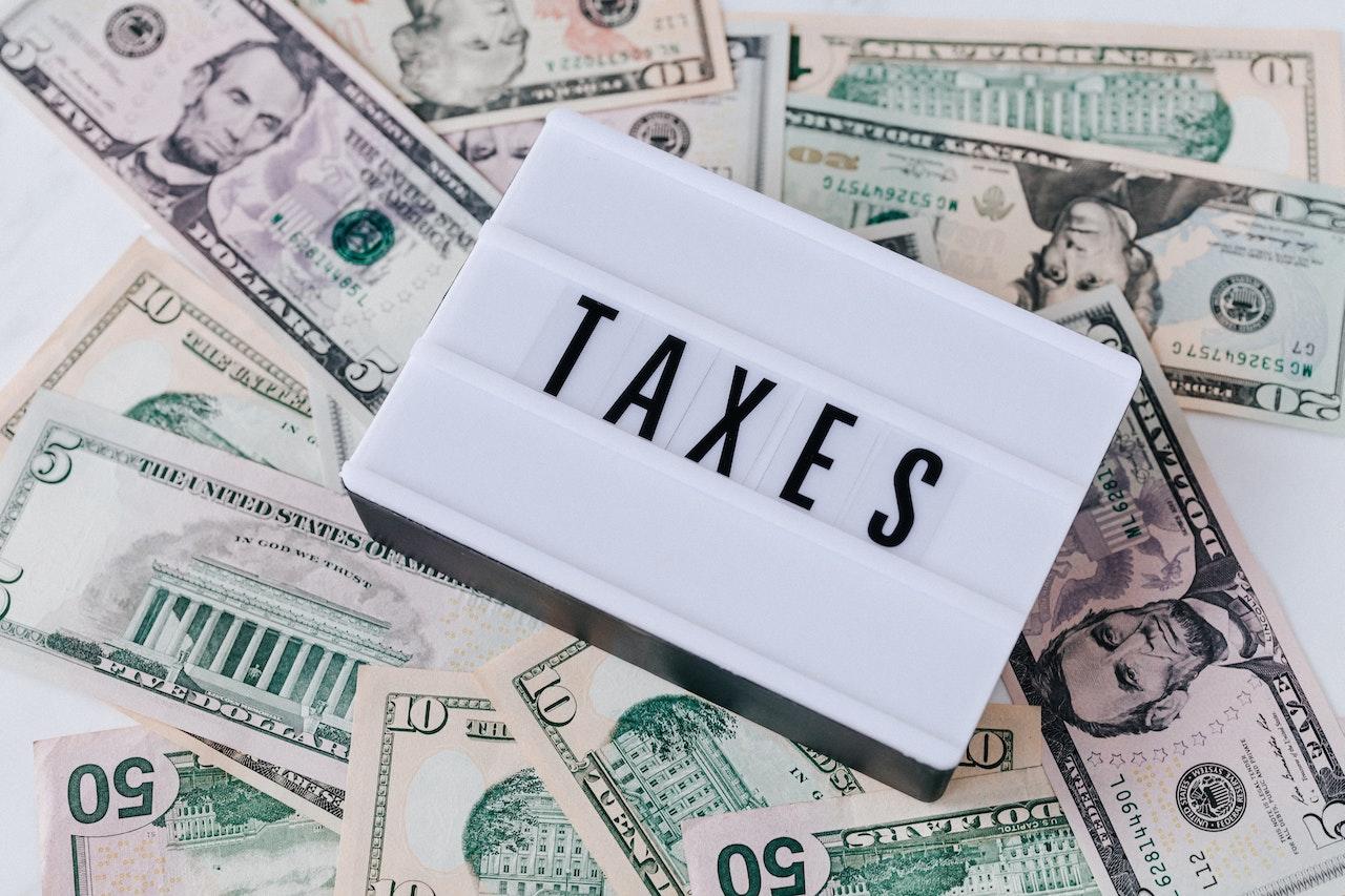Dollars américains avec un bloc écrit "taxes" posé dessus.