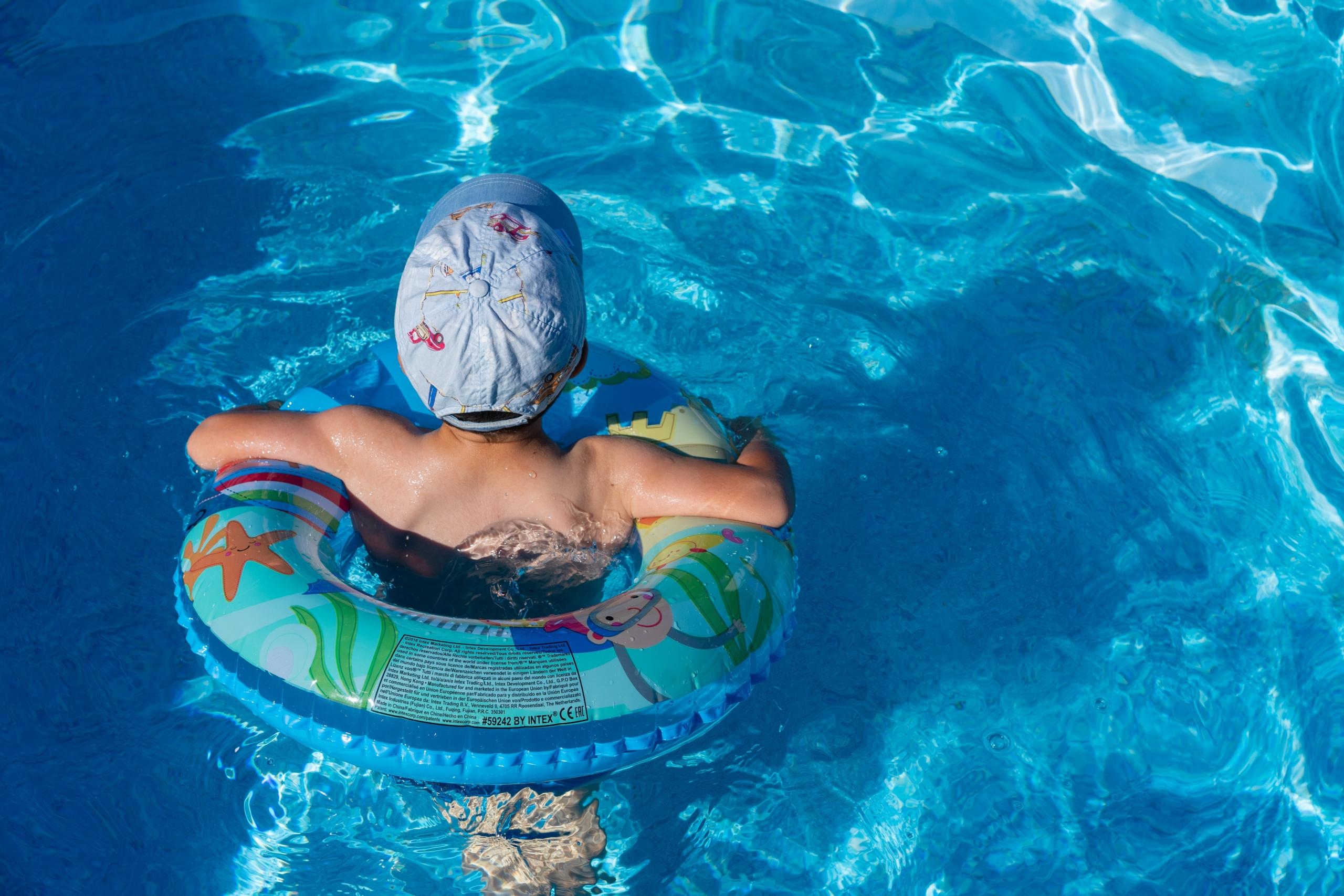 Un enfant avec une bouée dans une piscine.