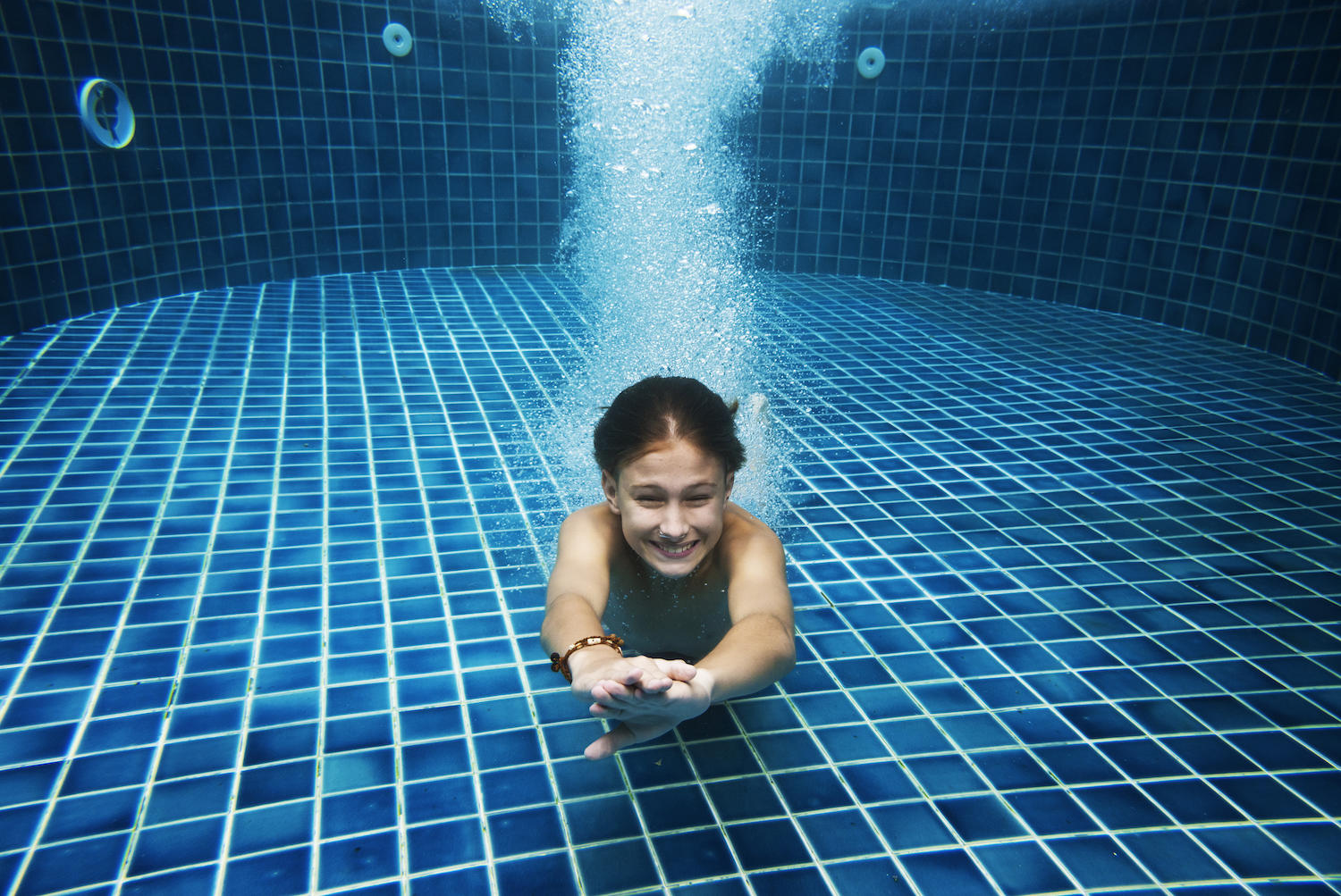 Jeune garçon nageant au fond d'une piscine.
