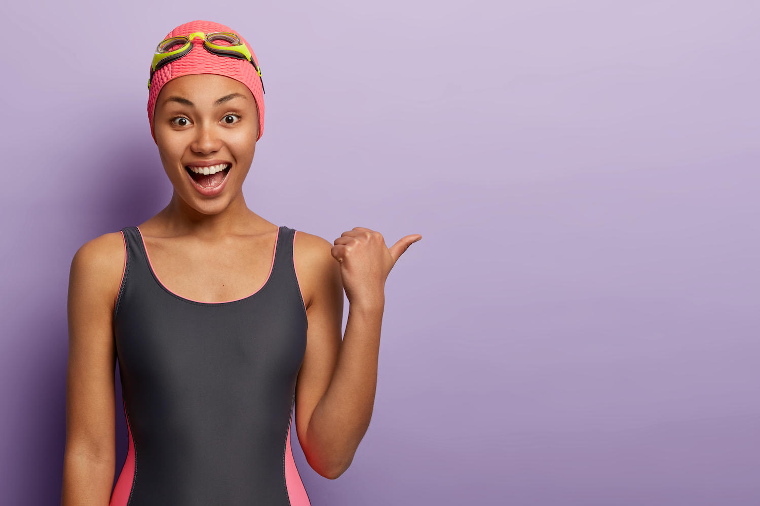 Une jeune femme avec maillot et bonnet de bain a l'air joyeux.