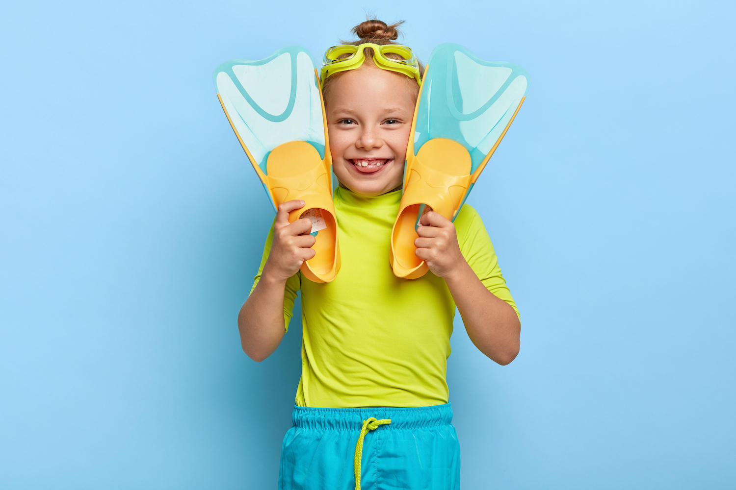 Petite fille avec des palmes et des lunettes de piscine fait une grimace.
