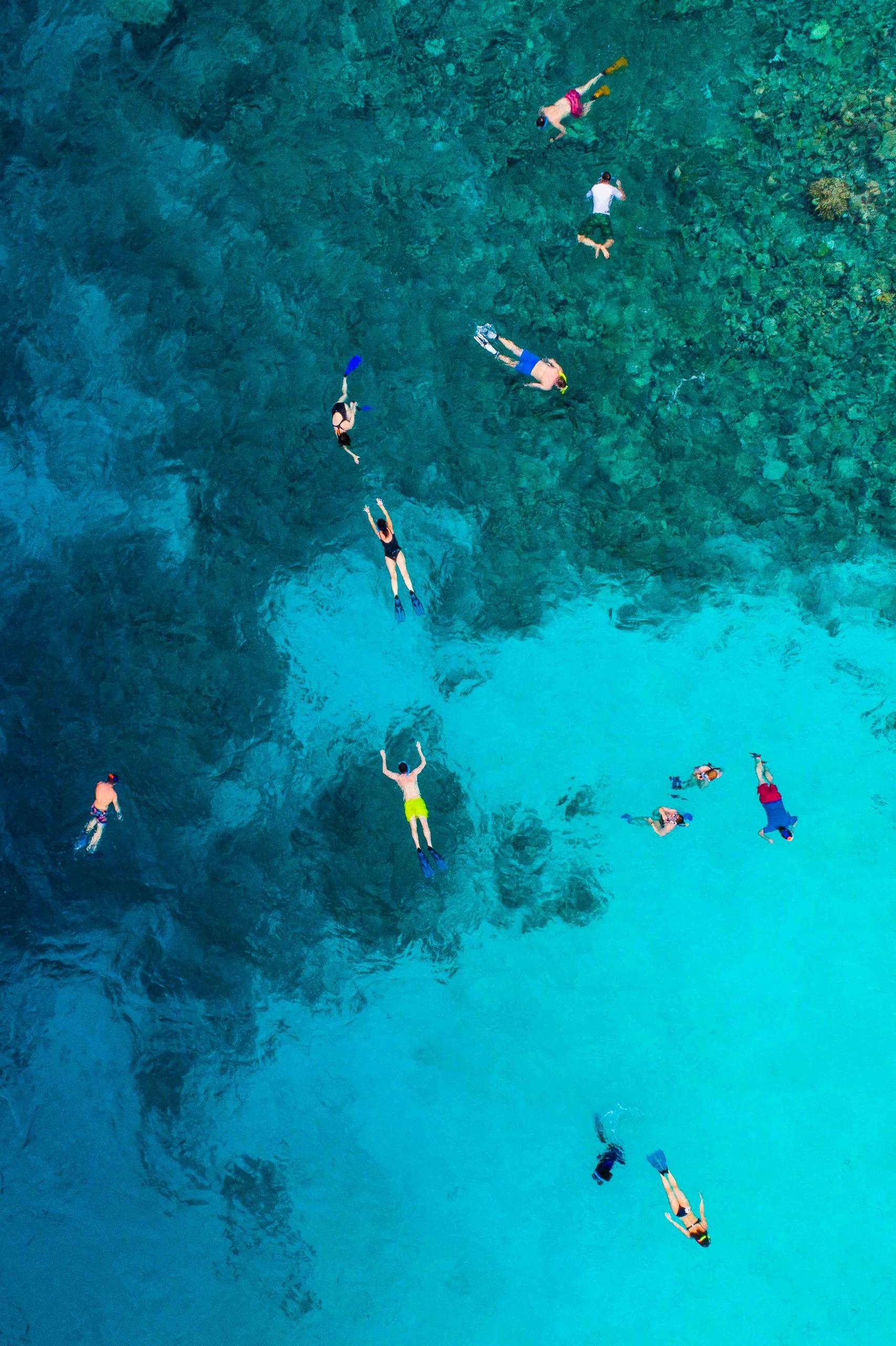 Des gens flottent à la surface de l'eau, vus d'en haut.