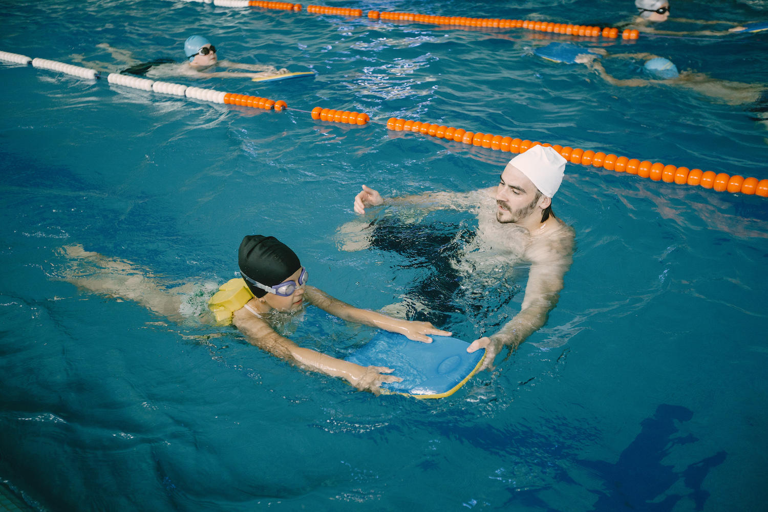 Un homme apprend à un enfant à nager dans une piscine.