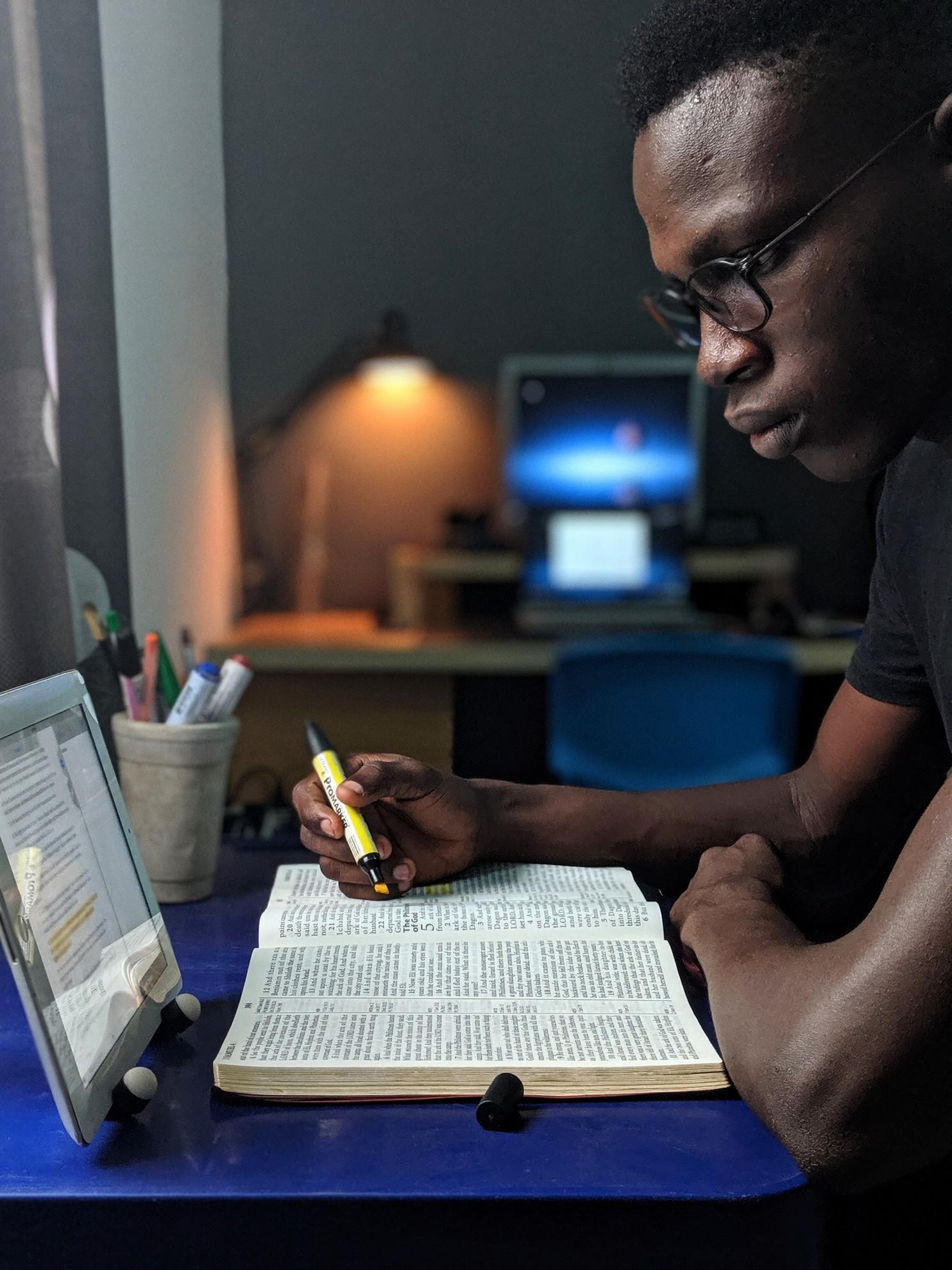 Un homme en train de surligner un texte dans un livre.