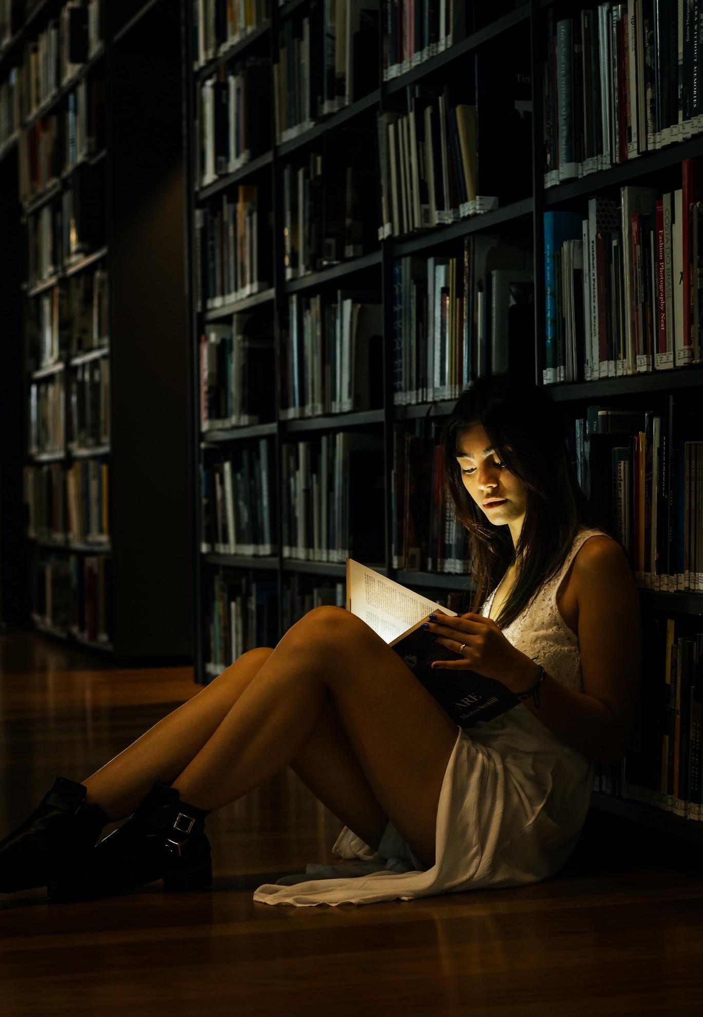 Une femme en train de lire un livre dans une bibliothèque.