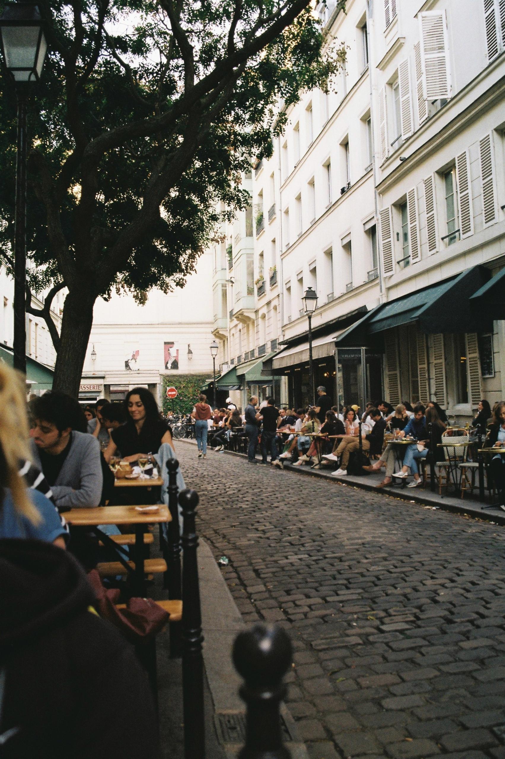 Une rue pavée remplie de terrasses parisiennes.