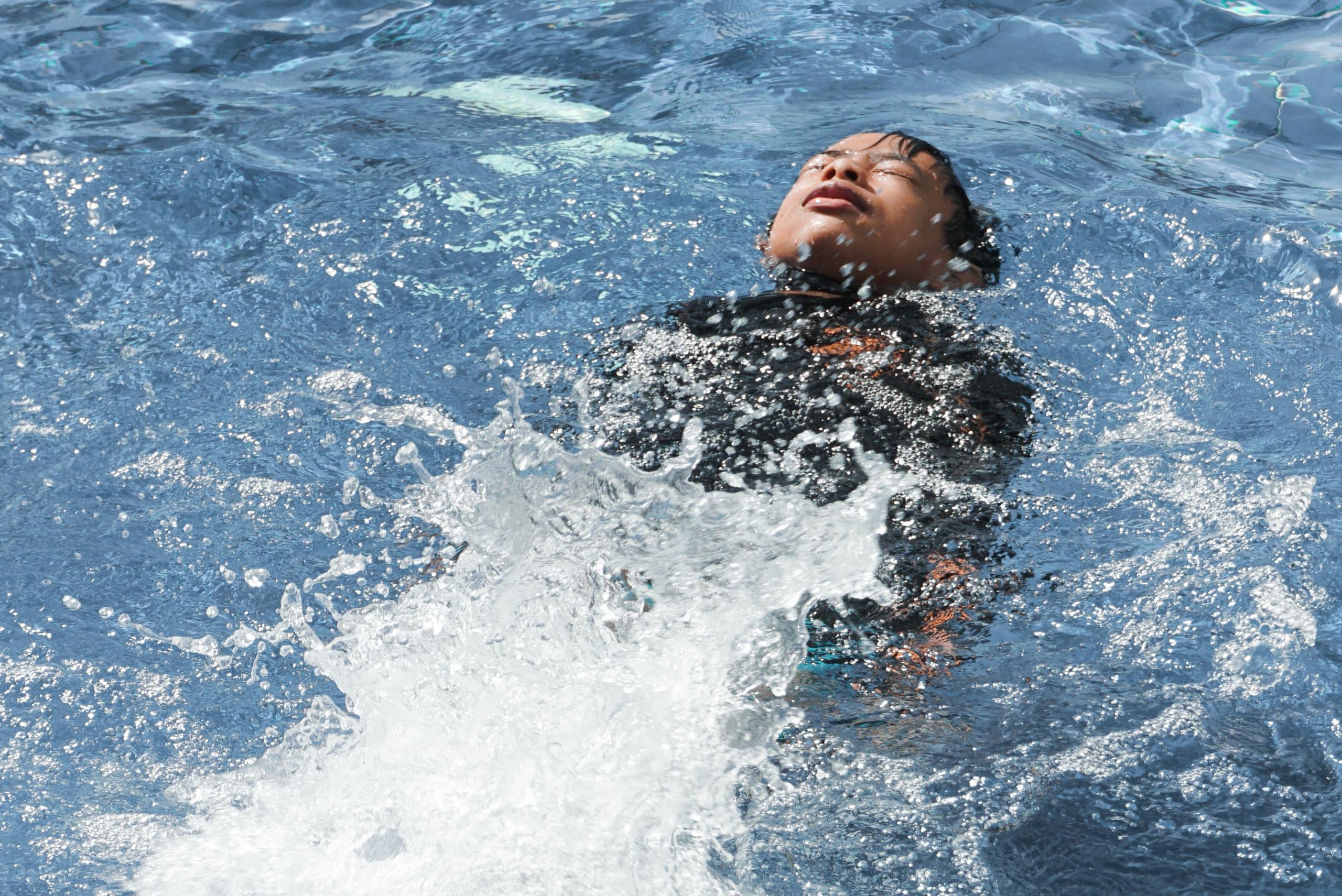 Un enfant nage sur le dos dans une piscine.