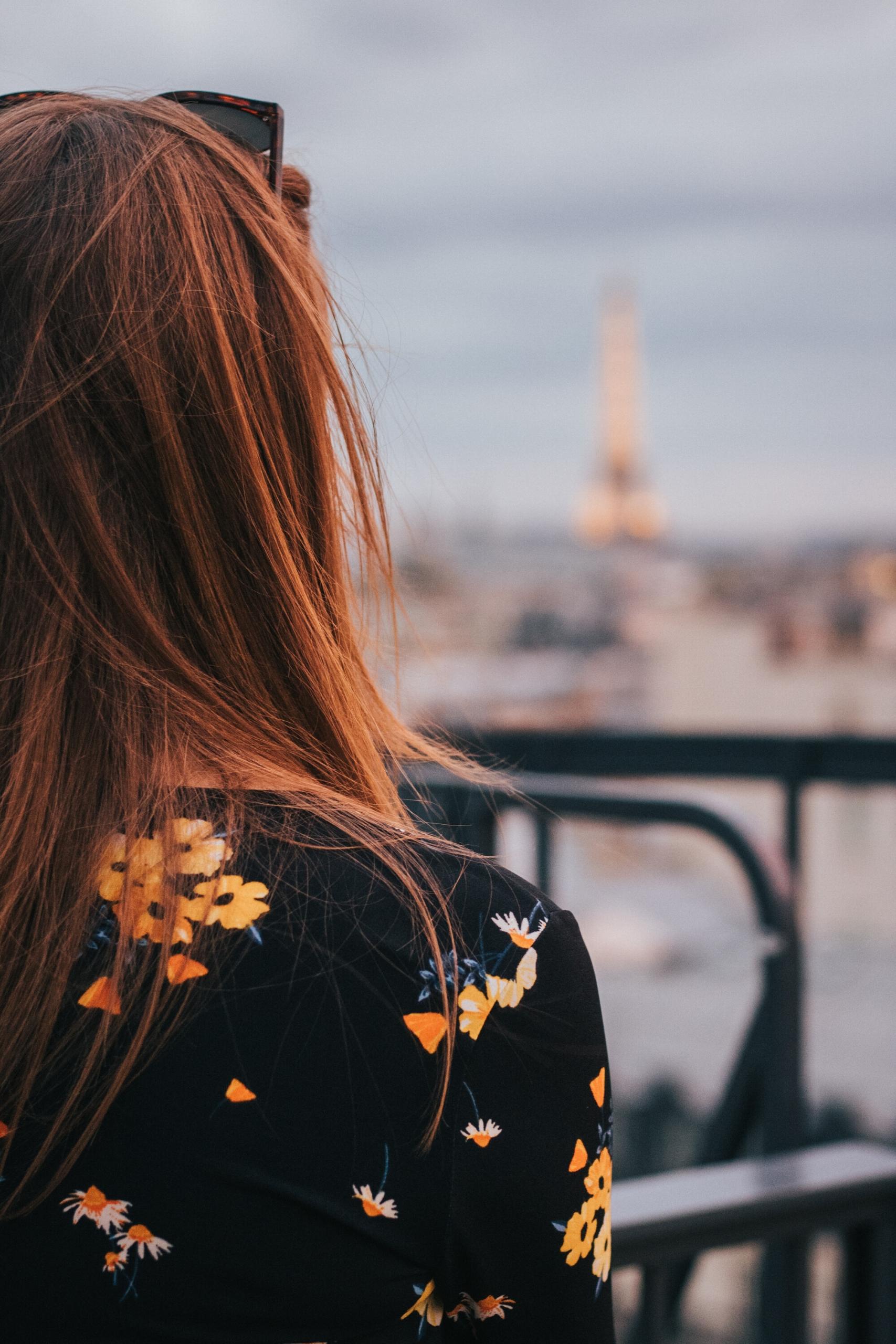 Une jeune fille de dos face à une vue de Paris.