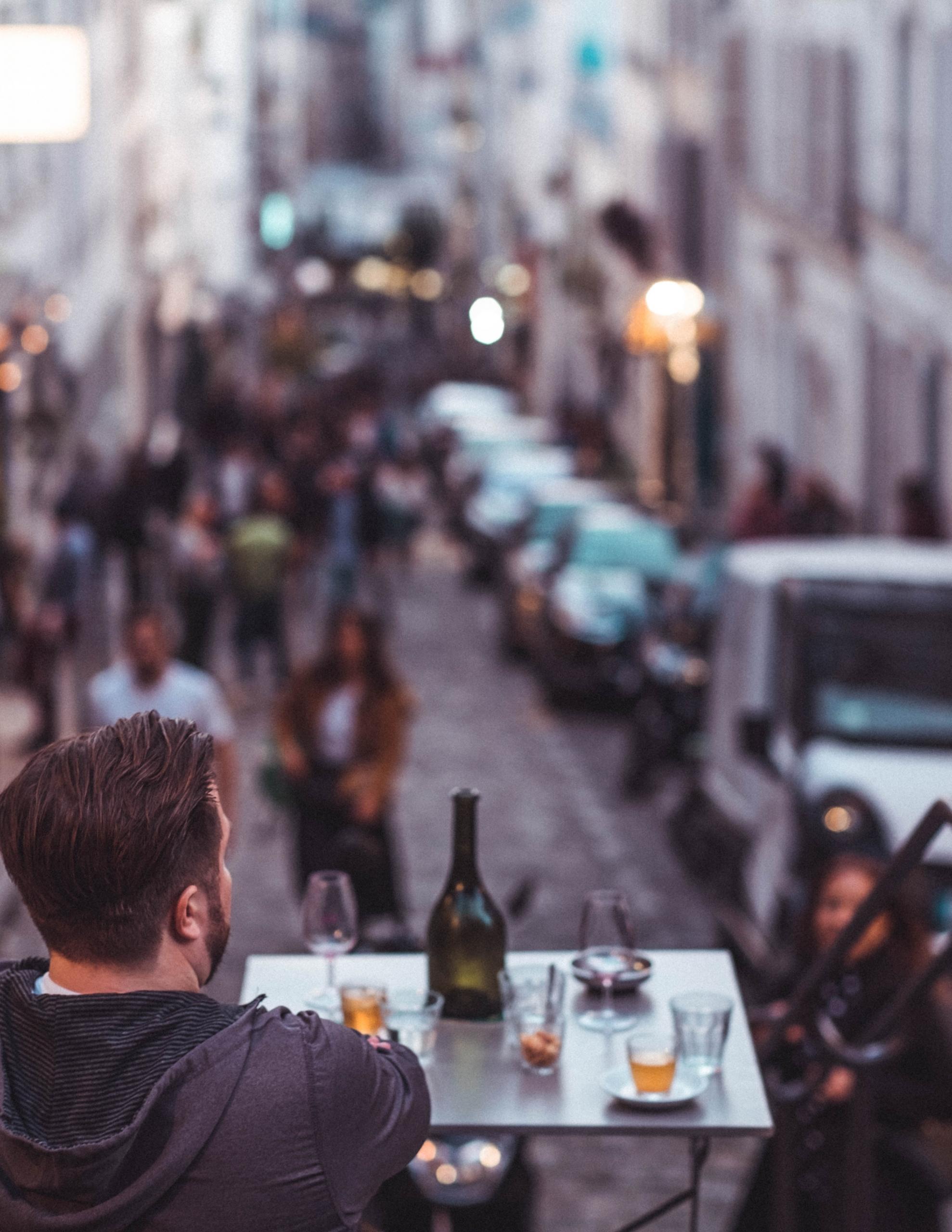 Une table de restaurant surplombe une rue parisienne.