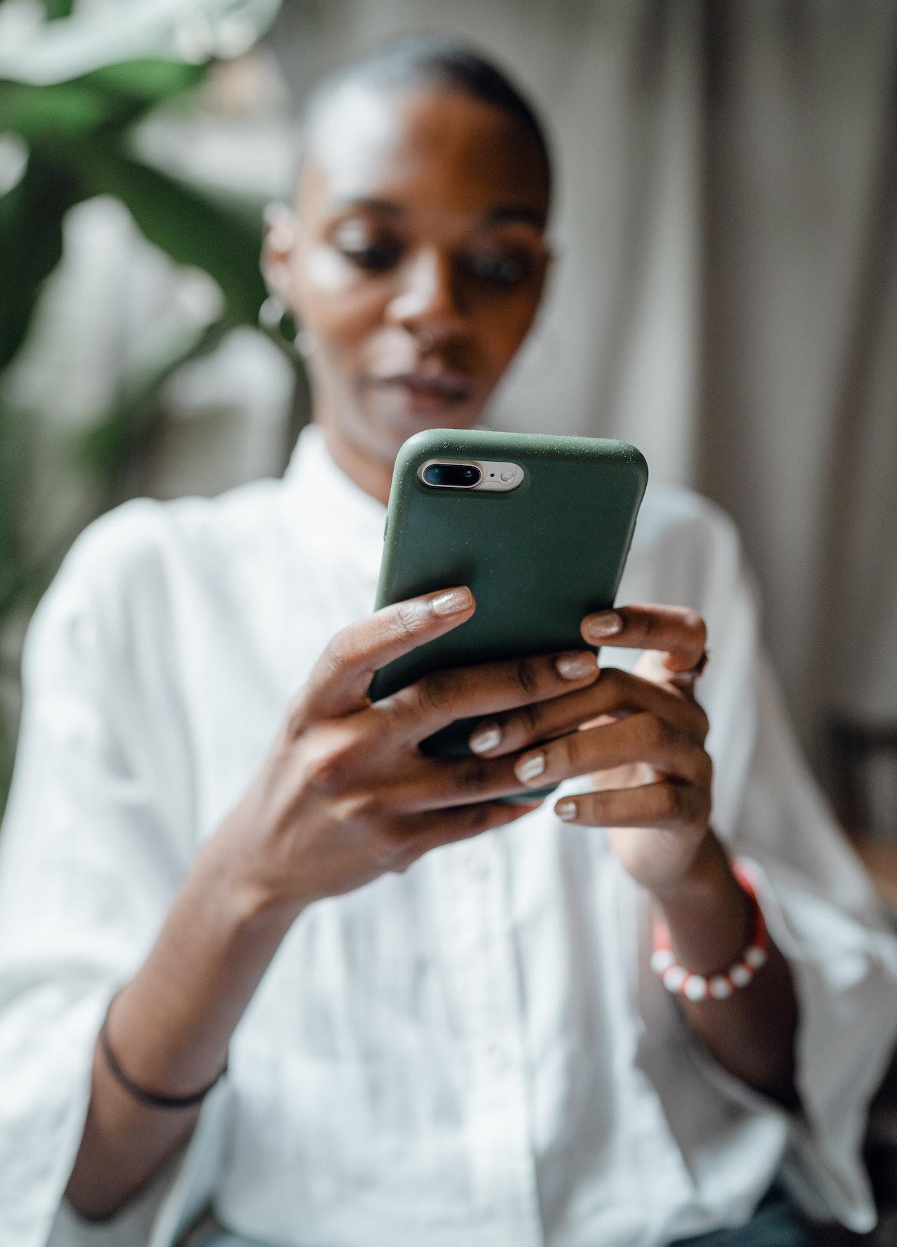 Jeune femme noir joue aux échecs sur son smartphone.