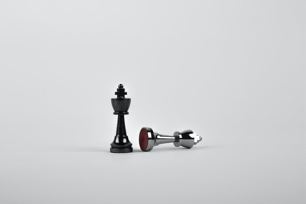 Deux pièces d'échecs, une noire debout et une blanche (grise) couchée.