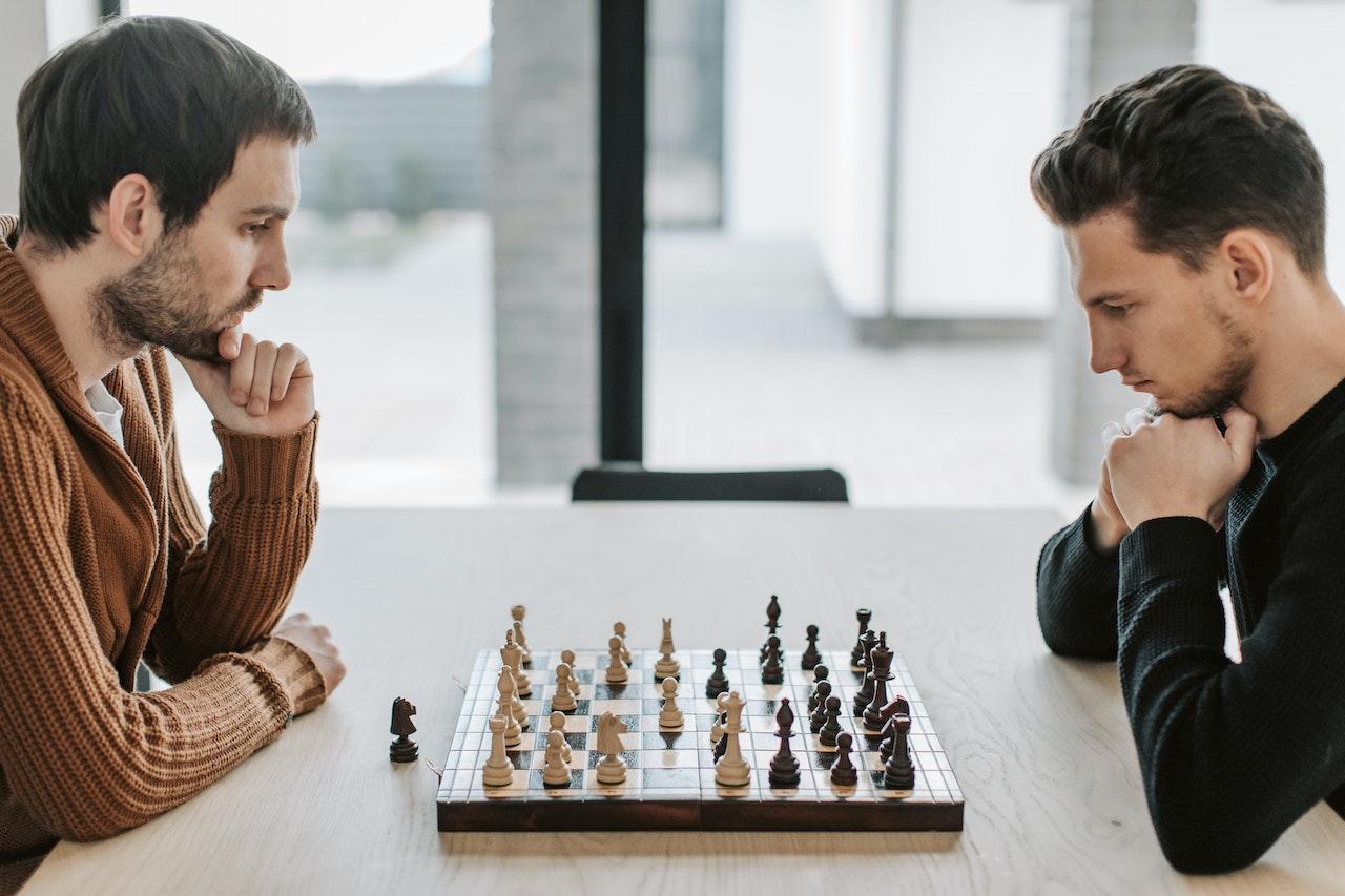 Deux hommes jouent aux échecs assis face à face.