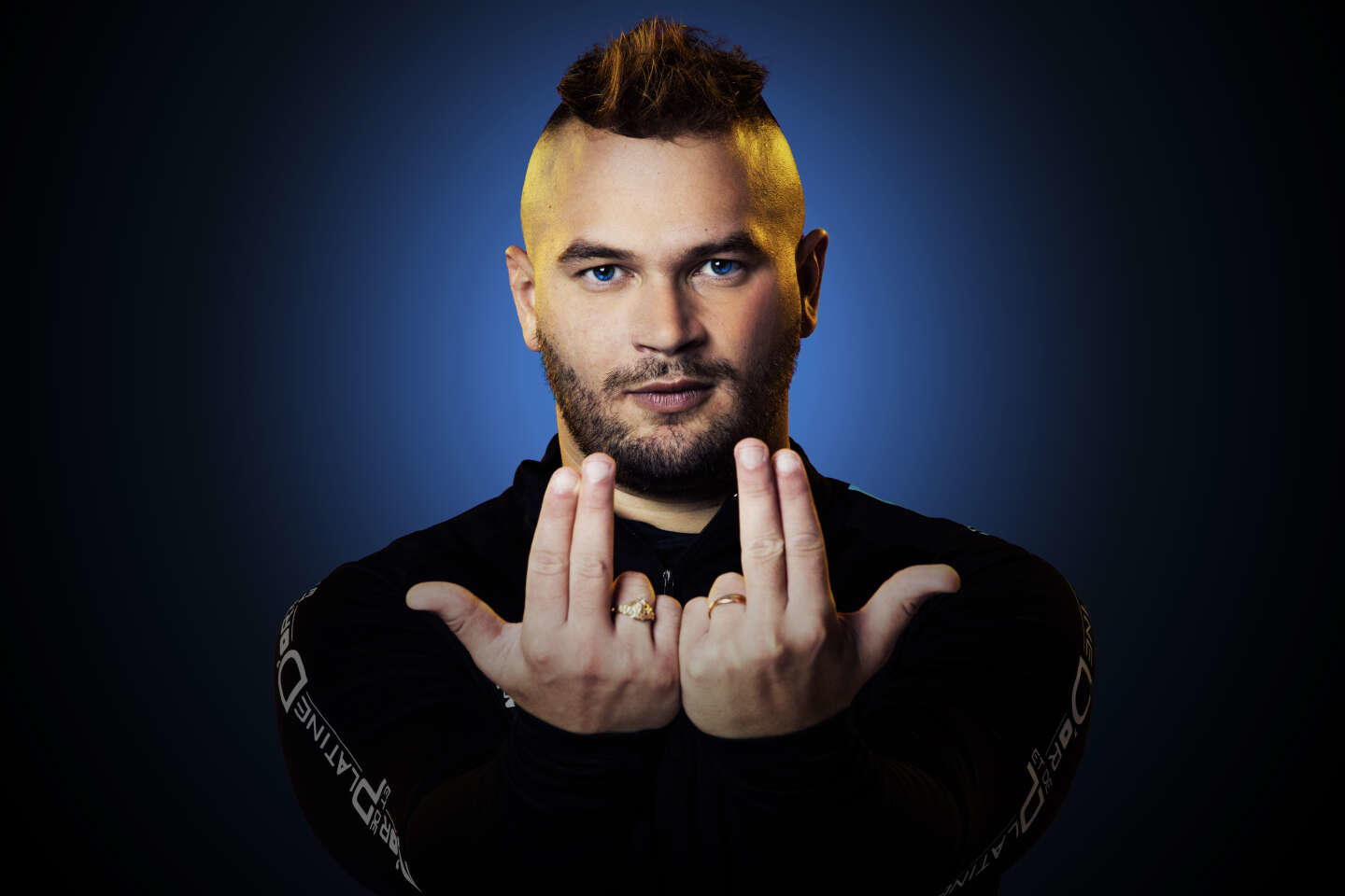 Le rappeur marseillais Jul forme le signe de doigt distinctif avec ses mains.