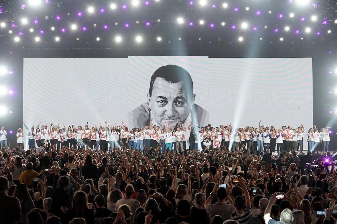 La scène du concert des Enfoirés avec une photo de Coluche en fond.